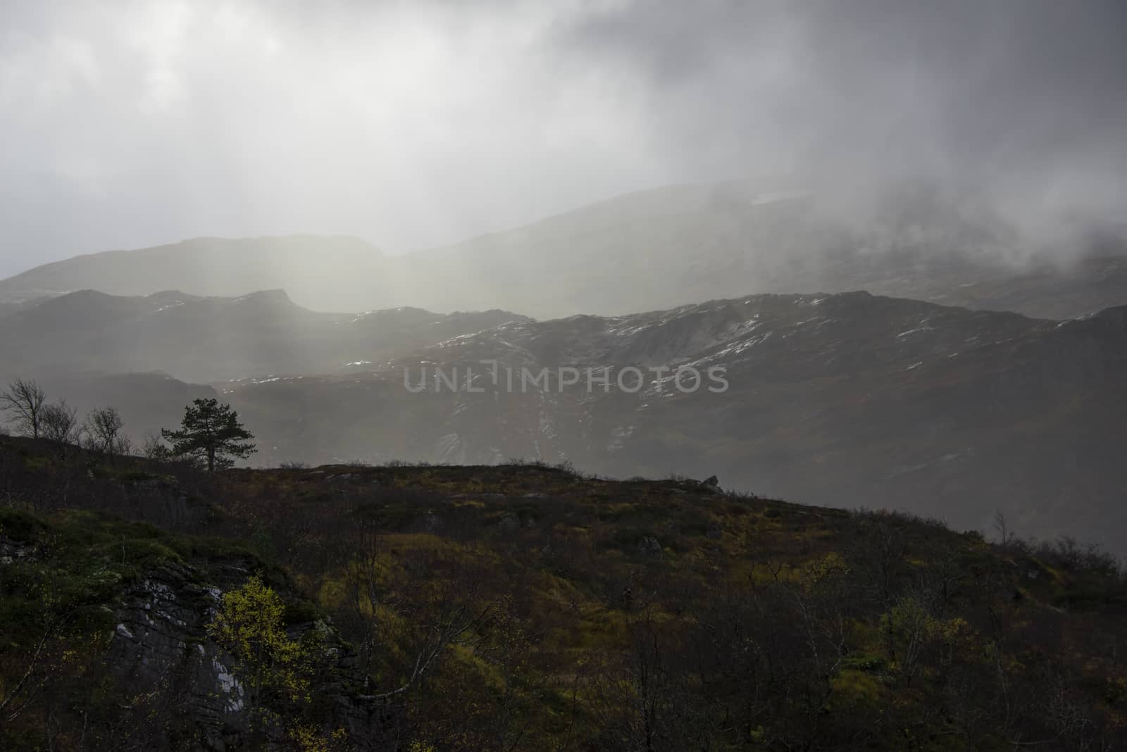 Heavy clouds, light beams and rain in the mountain