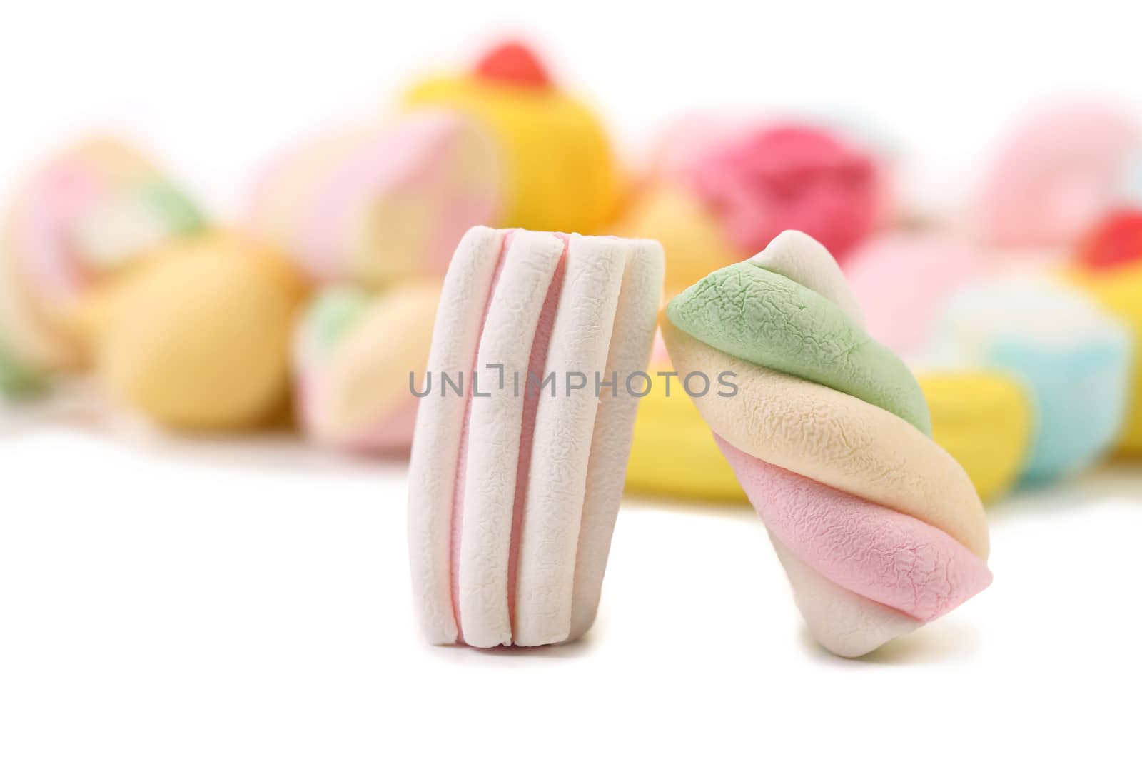 Two colourful marshmallow on background of other. Close up. White background.