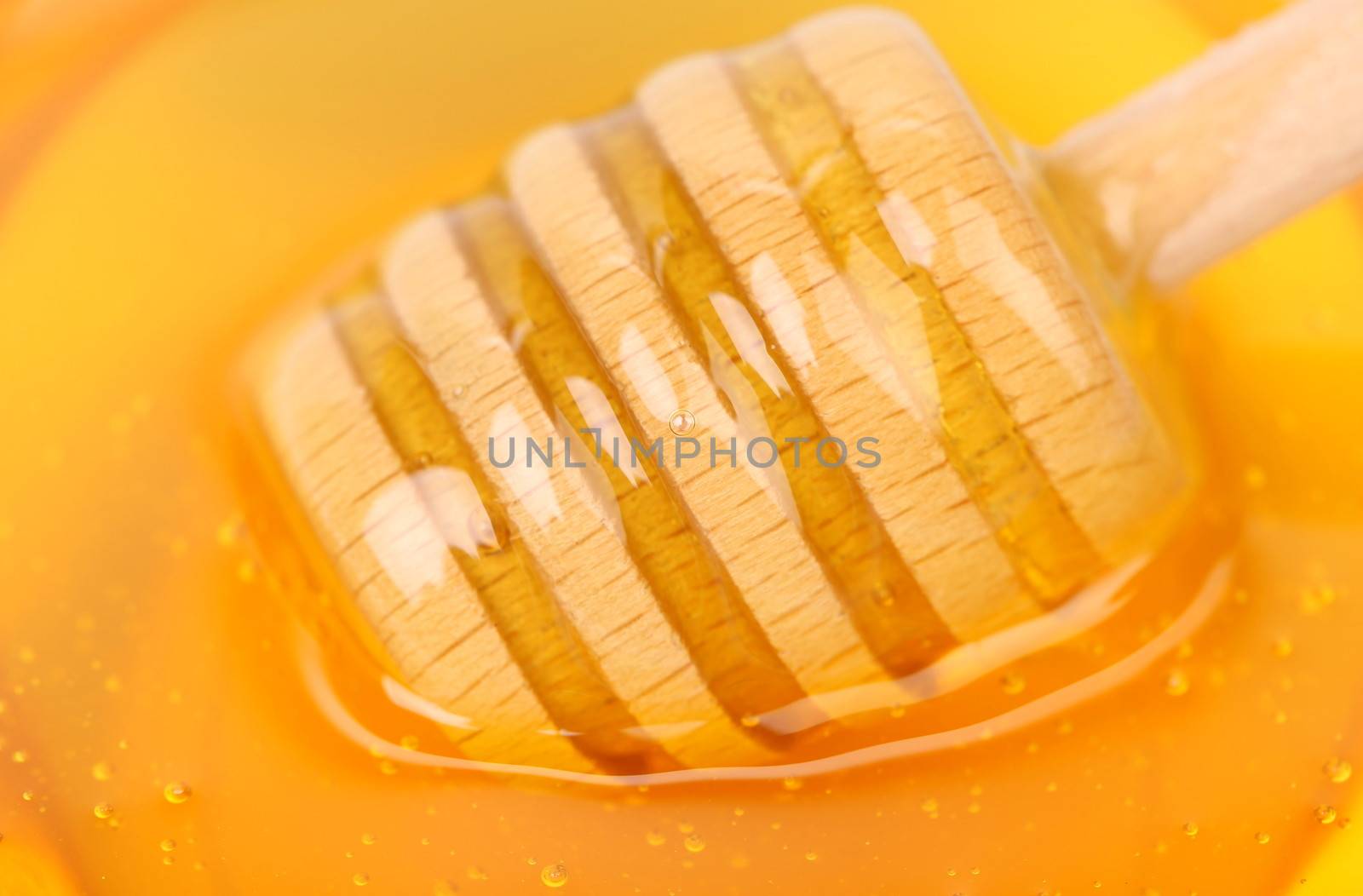 Bee honey with wooden dipper. Honey's dessert - honey stick on golden background.