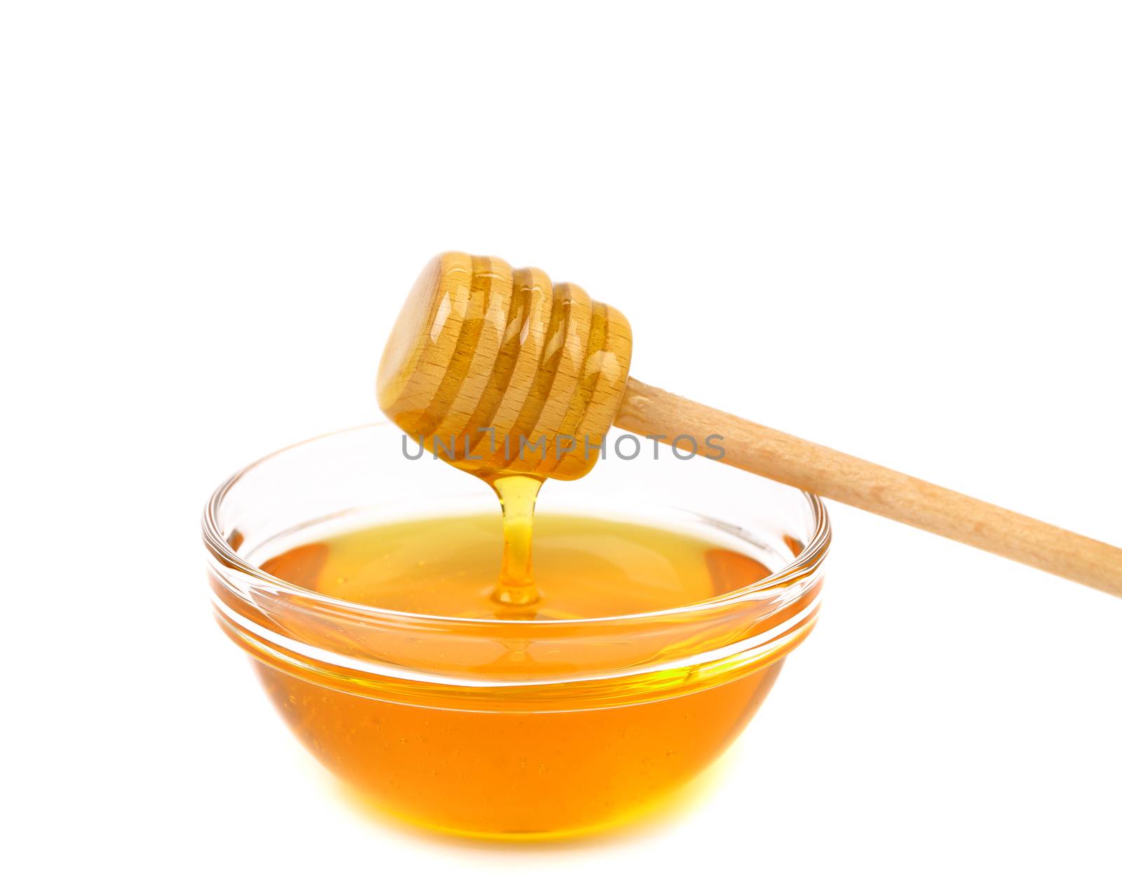 Honey dripping from a wooden honey dipper on white background