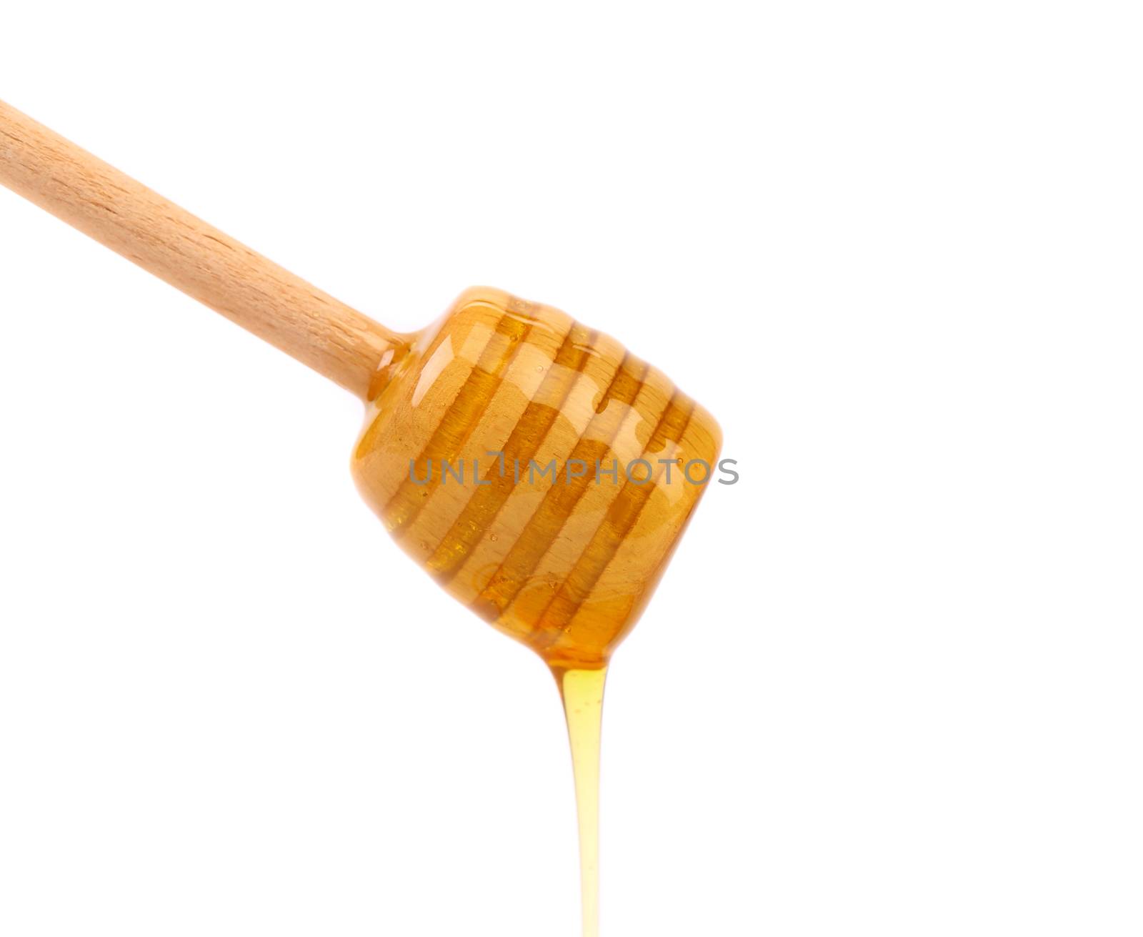 Honey dripping from a wooden honey dipper on a white background