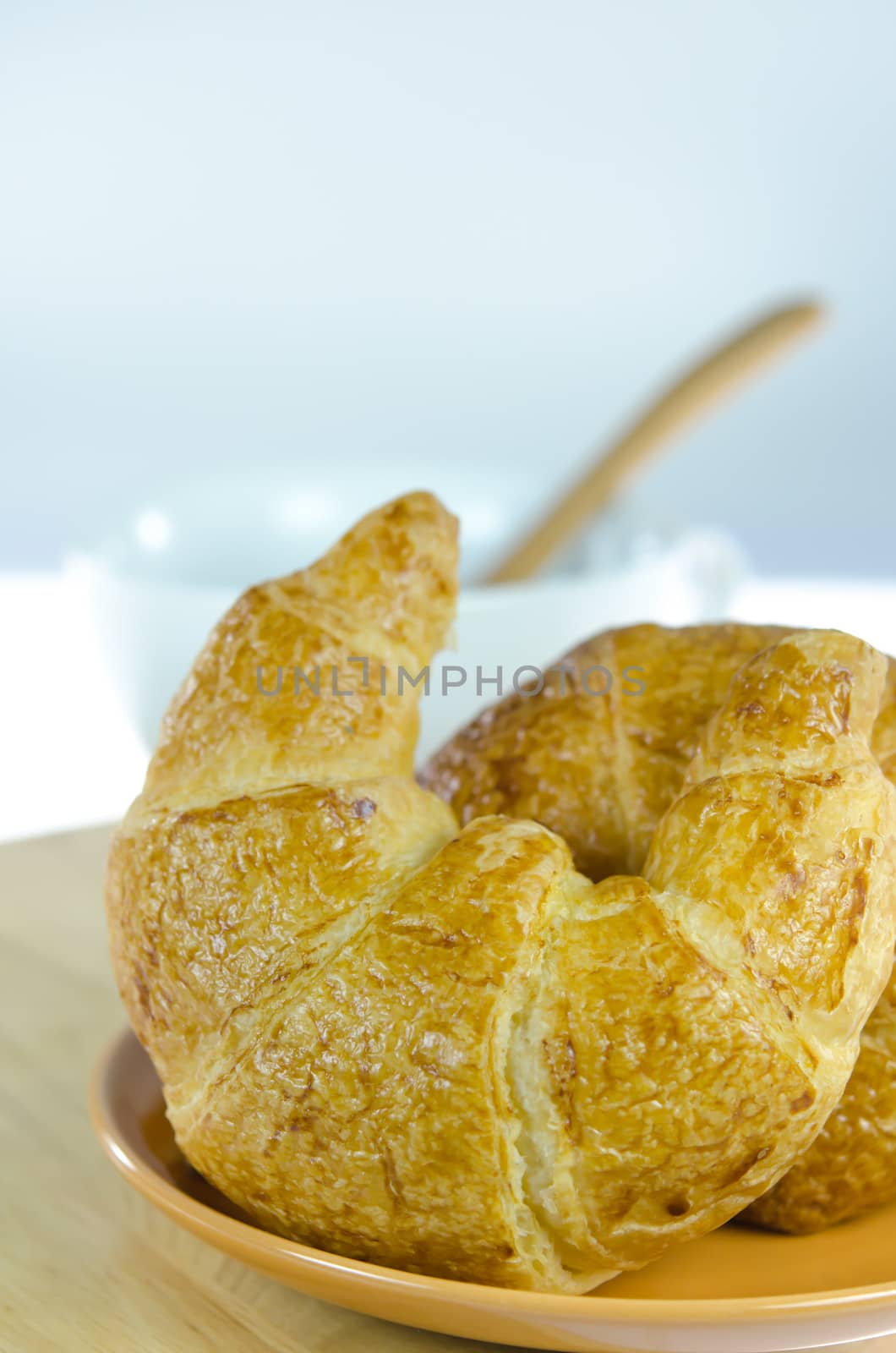 close up  croissants on  brown dish  and a white  cup of coffee with spoon , fresh food