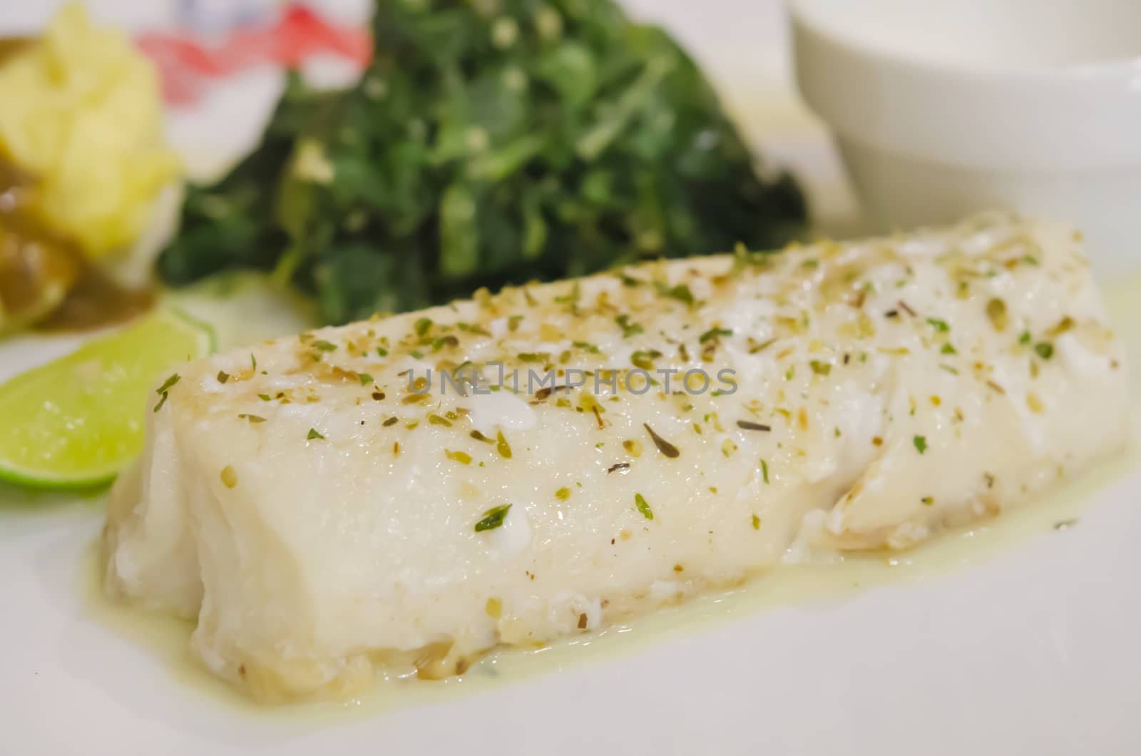 close up fillet fish steak with spinach on white plate