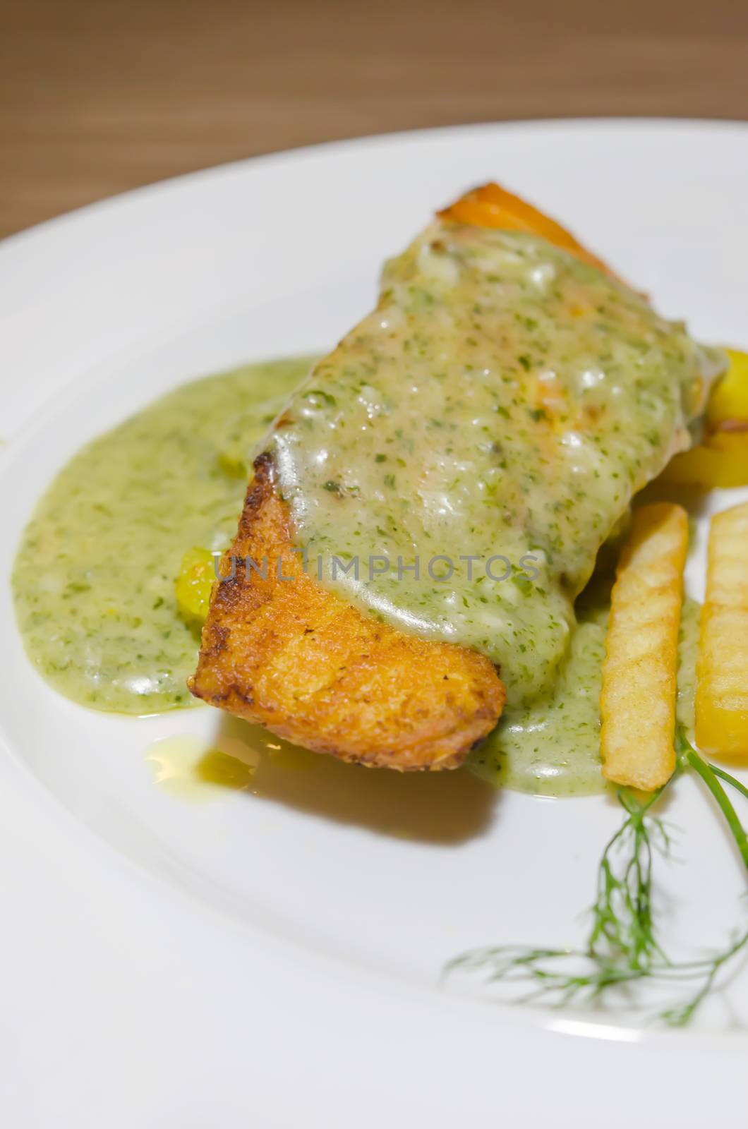 close up grilled  salmon served with green sauce and french fries 