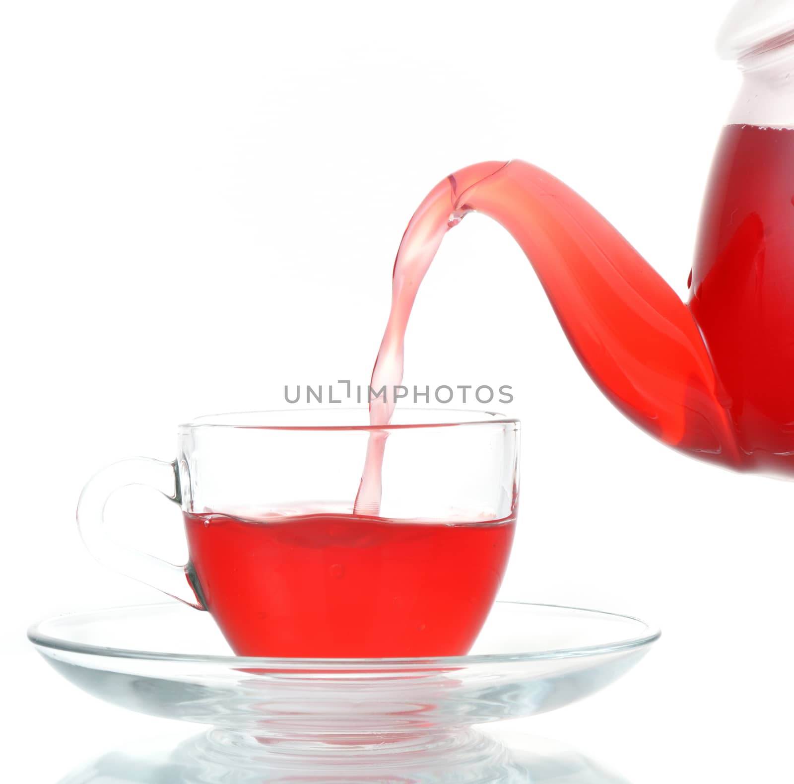 Tea being poured into glass tea cup isolated on a white background