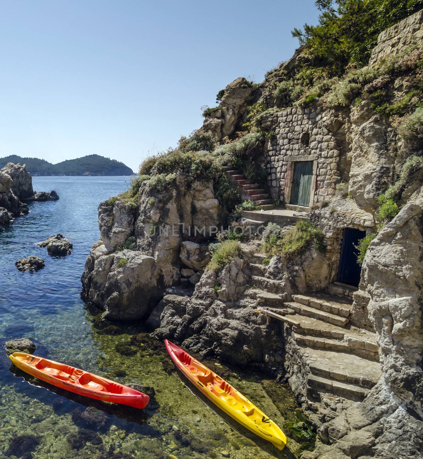 Pair of kayaks in front of a cliffside warehouses.