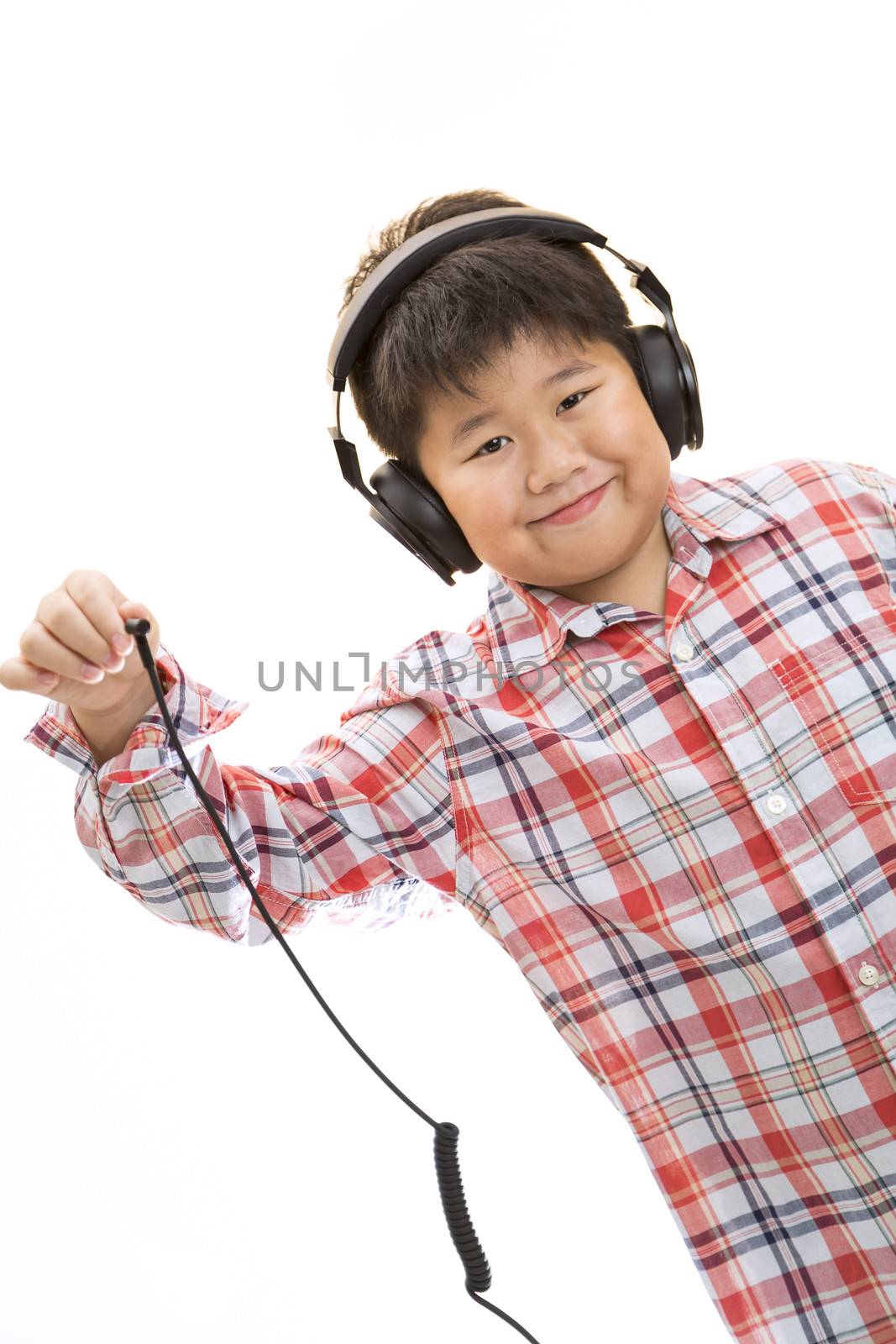 A smiling boy unplug his headphone on isolated background.