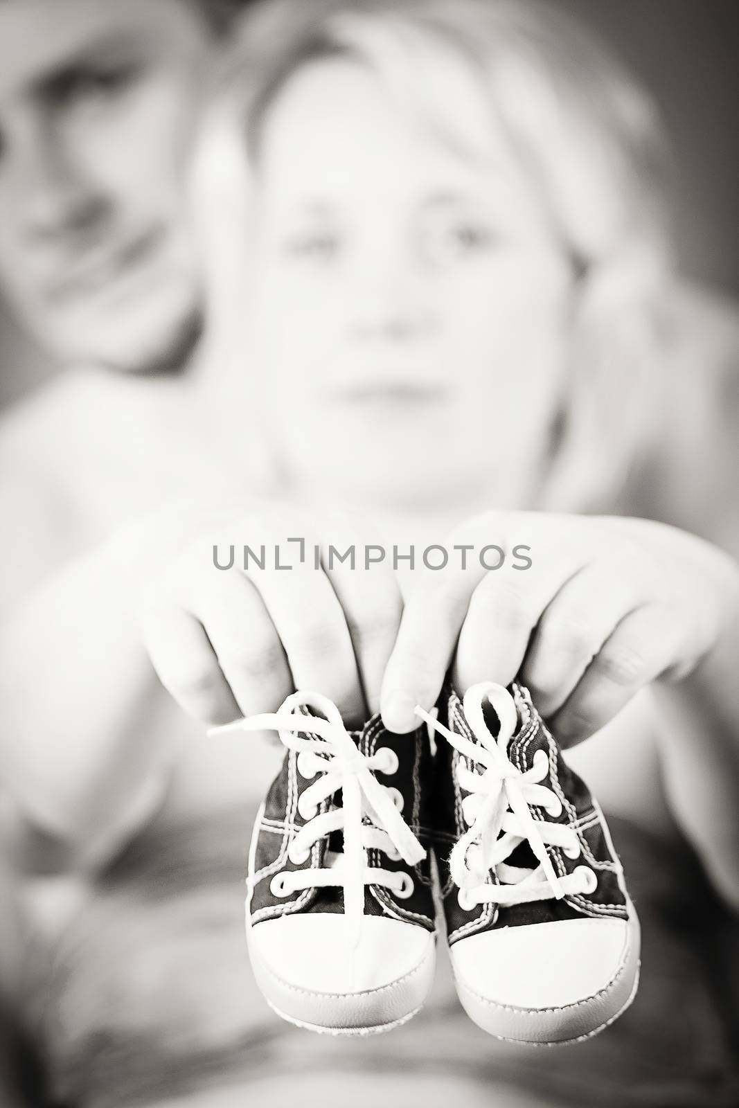 pregnant woman and husband with a child's shoe by artush