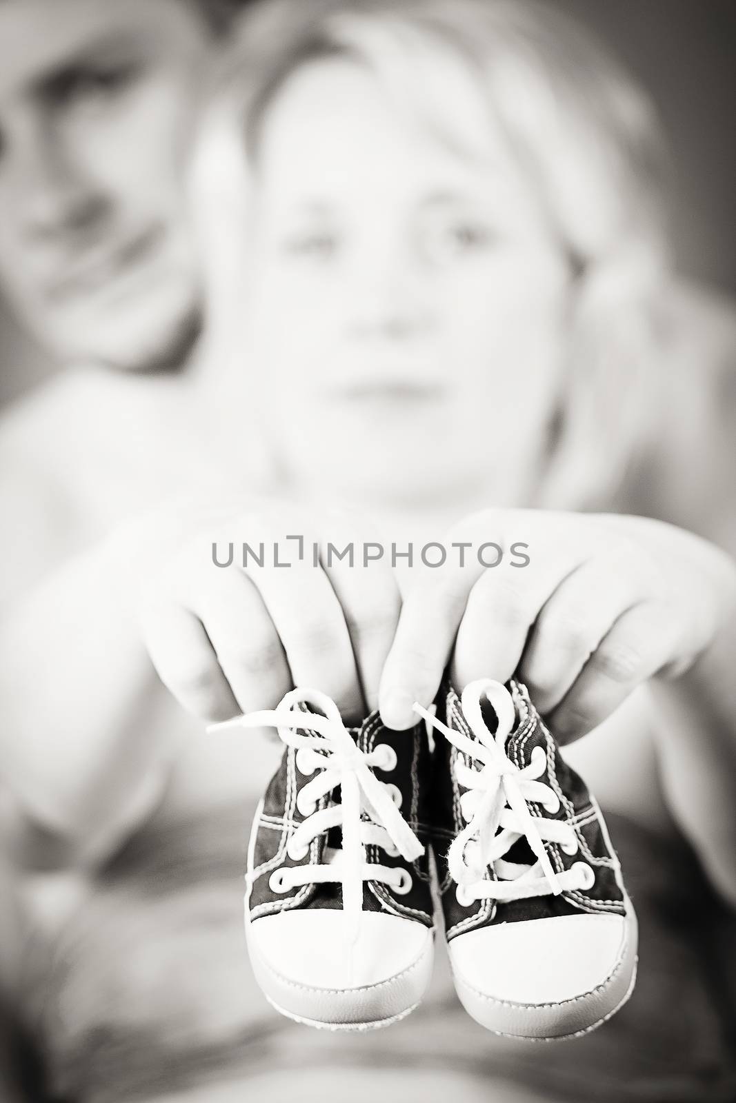 couple in love with a child's shoe and man tenderly holding her tummy with hand