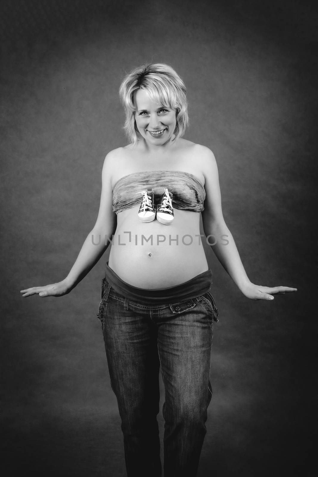 beautiful smiling pregnant woman with child boots on her tummy