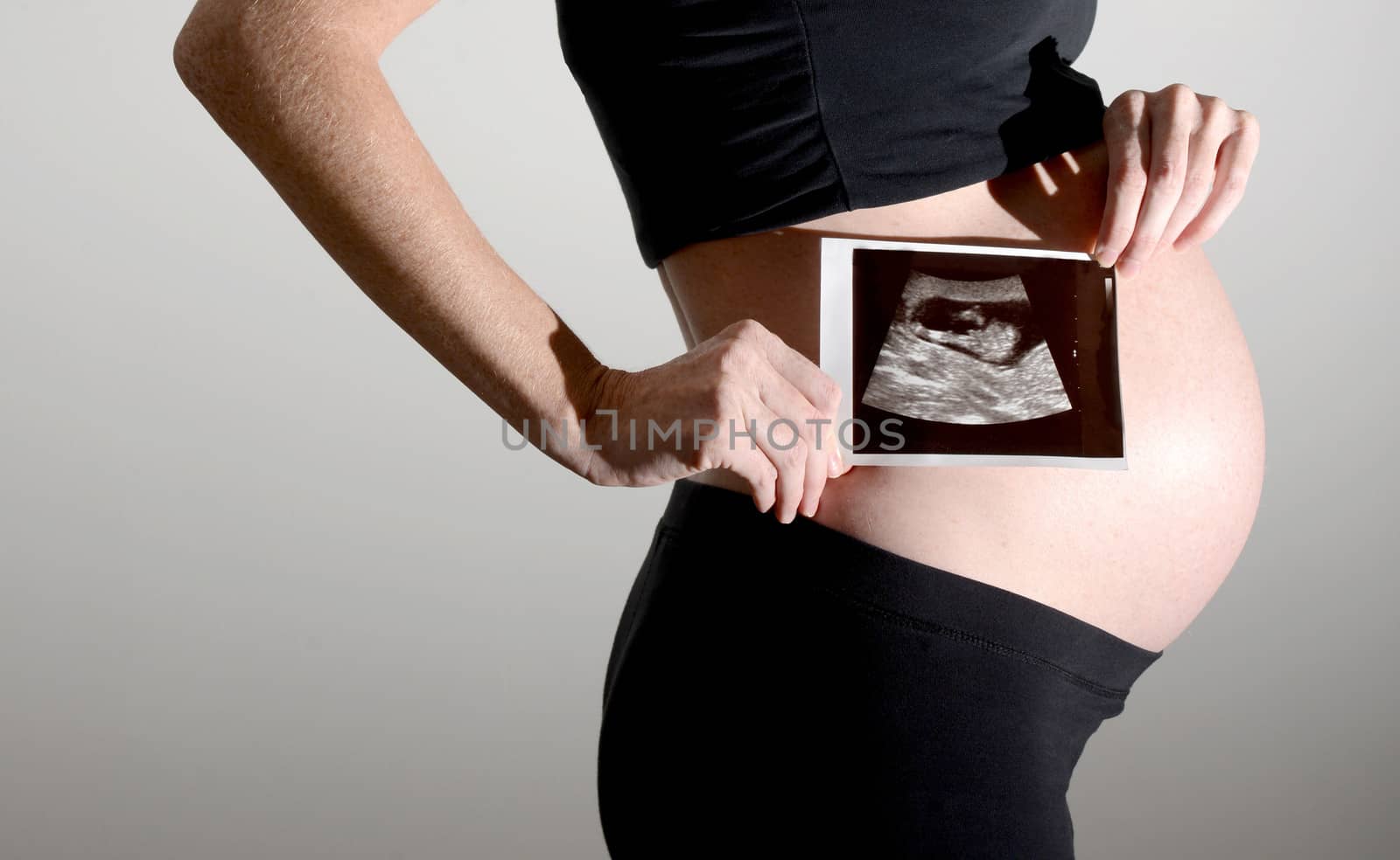pregnant woman holding ultrasound of unborn child