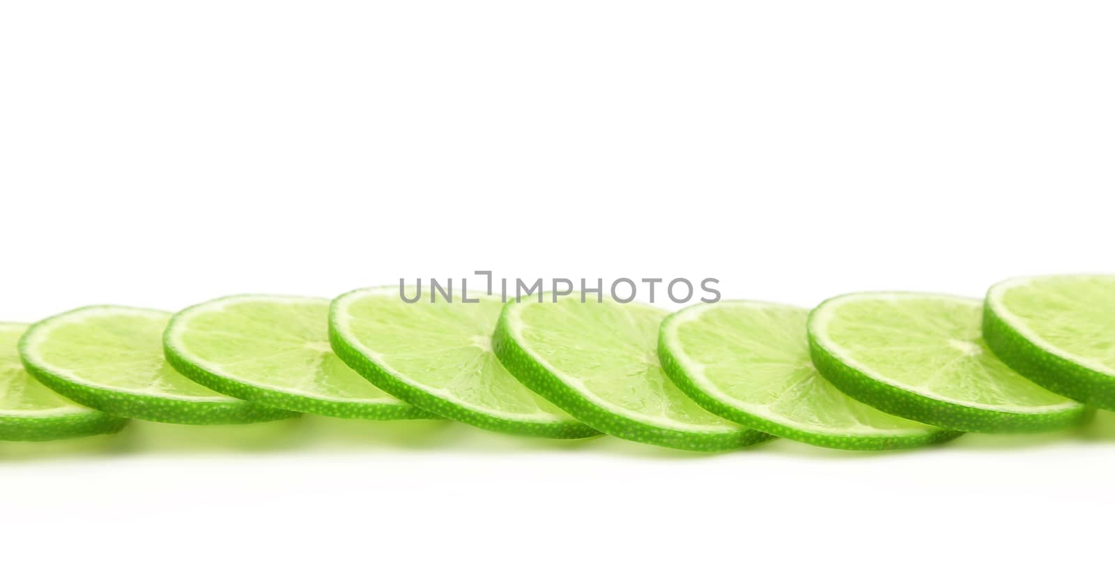 Slices of green lemon on a white background