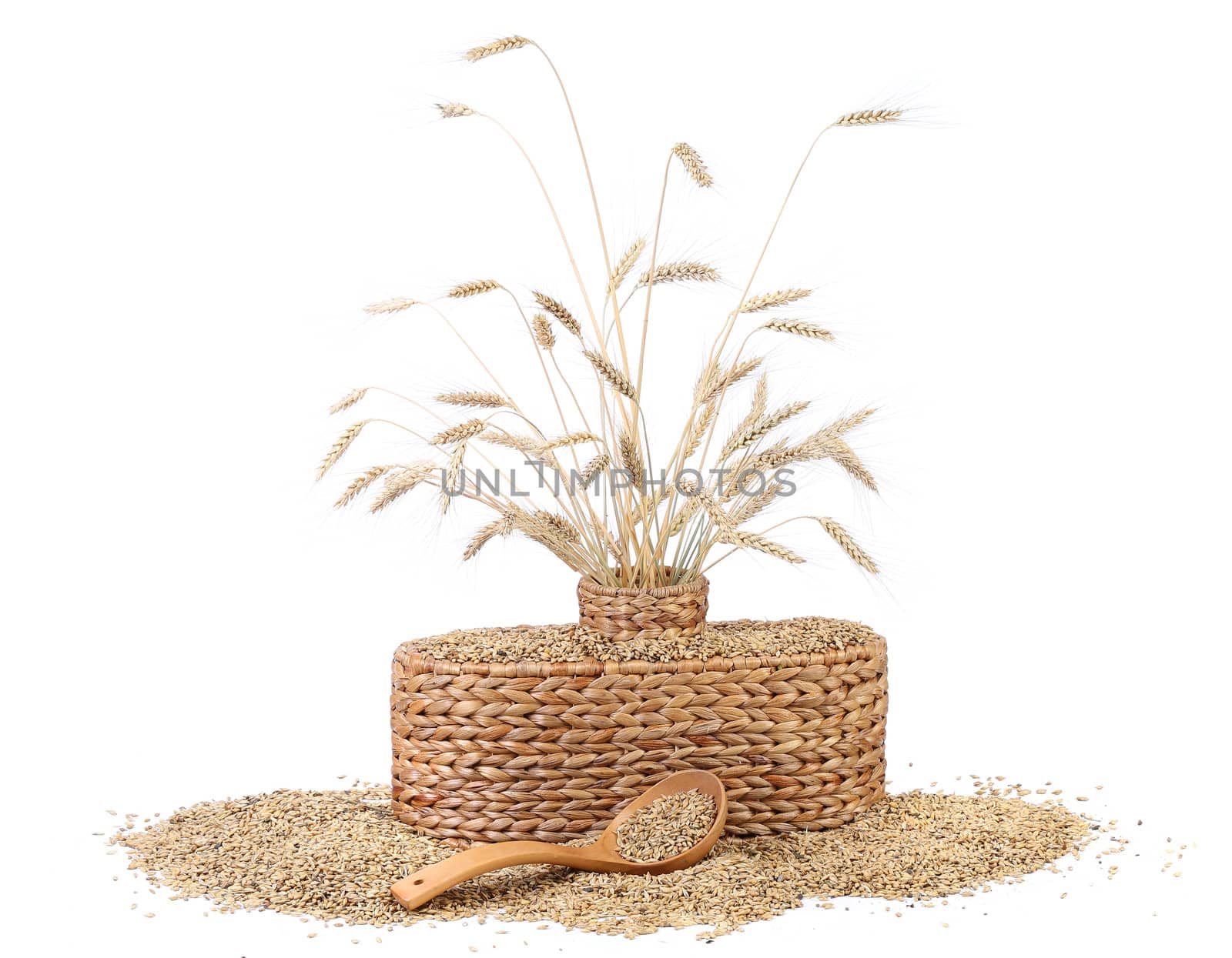 Wicker vase with ears of wheat, wheat grains, wooden spoon
