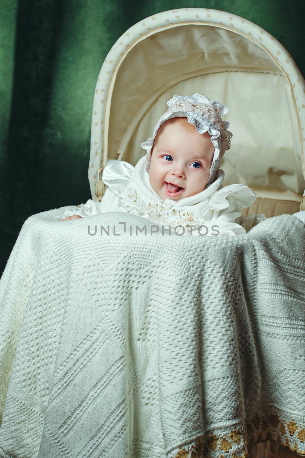 Cheerful and happy blue-eyed baby in  bonnet lies in cradle