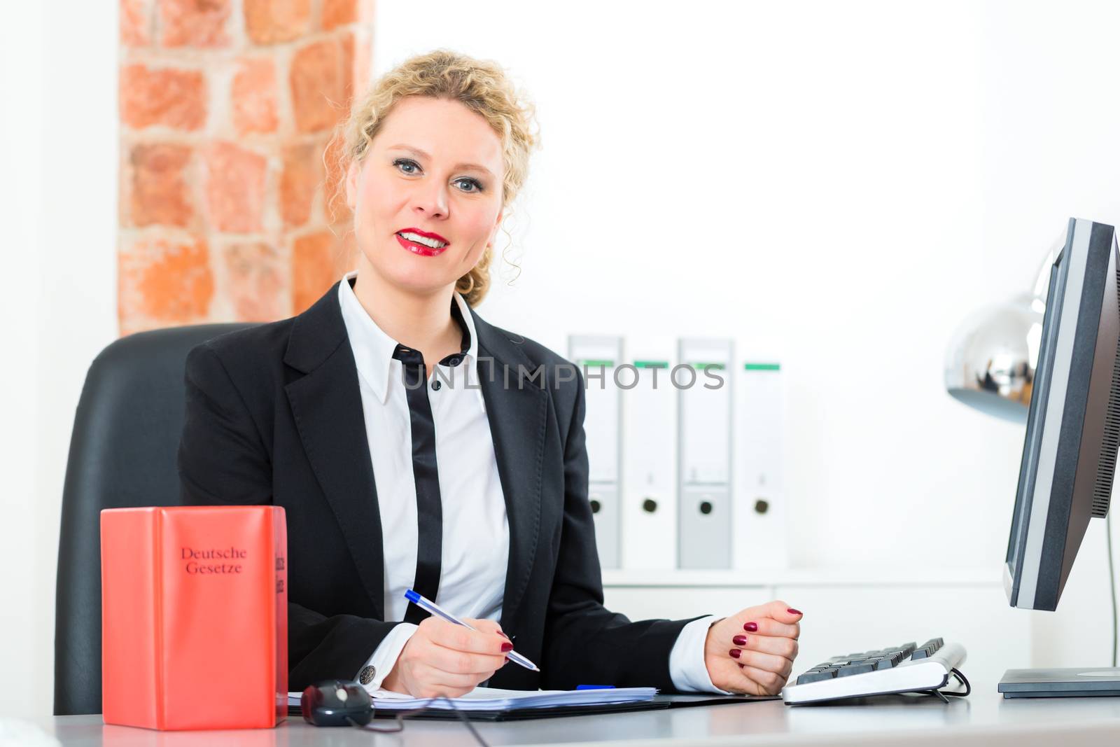 Young female lawyer working in her office with typical law book and writing document