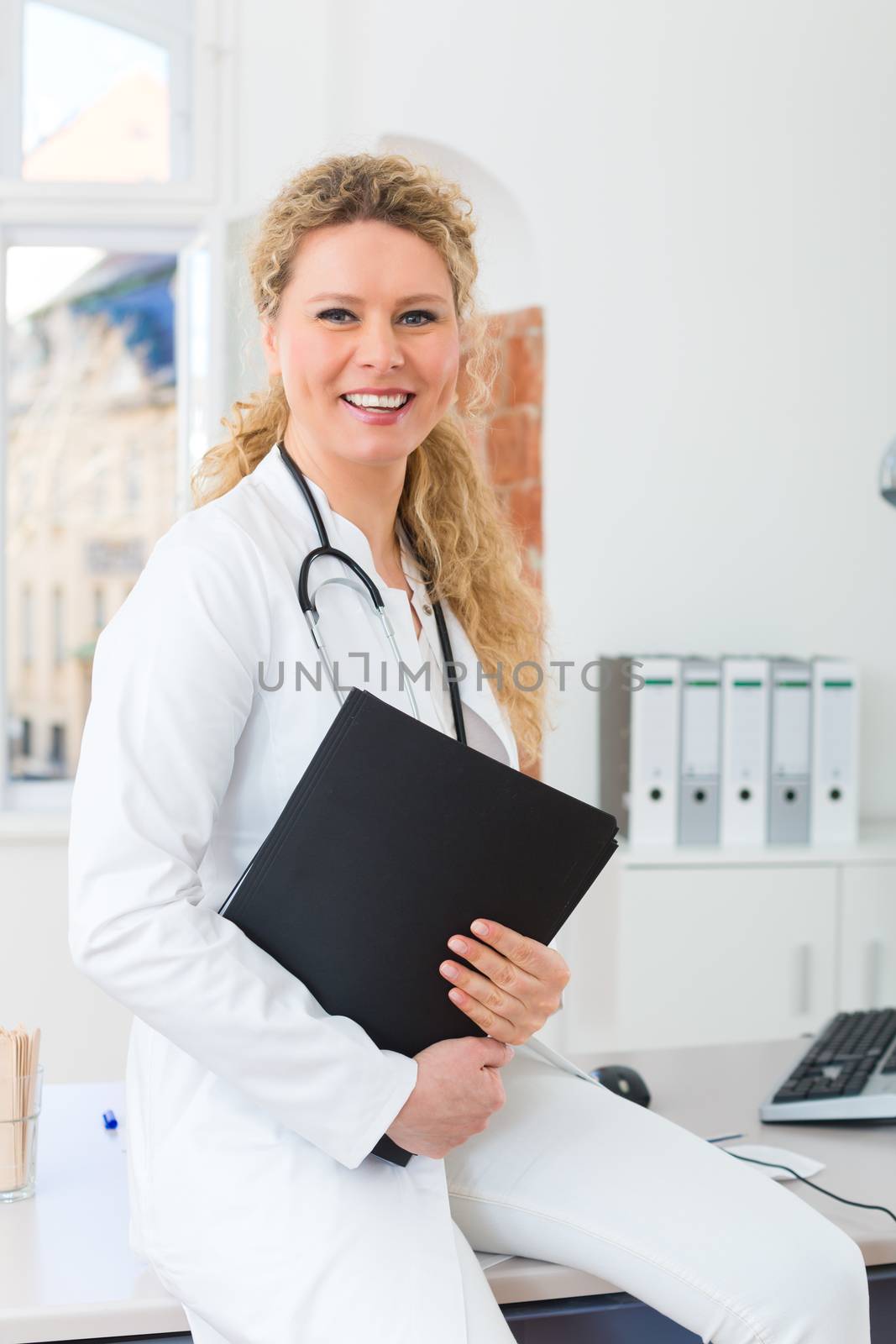 Young female doctor sitting on desk in front of clinic window with test result file or dossier