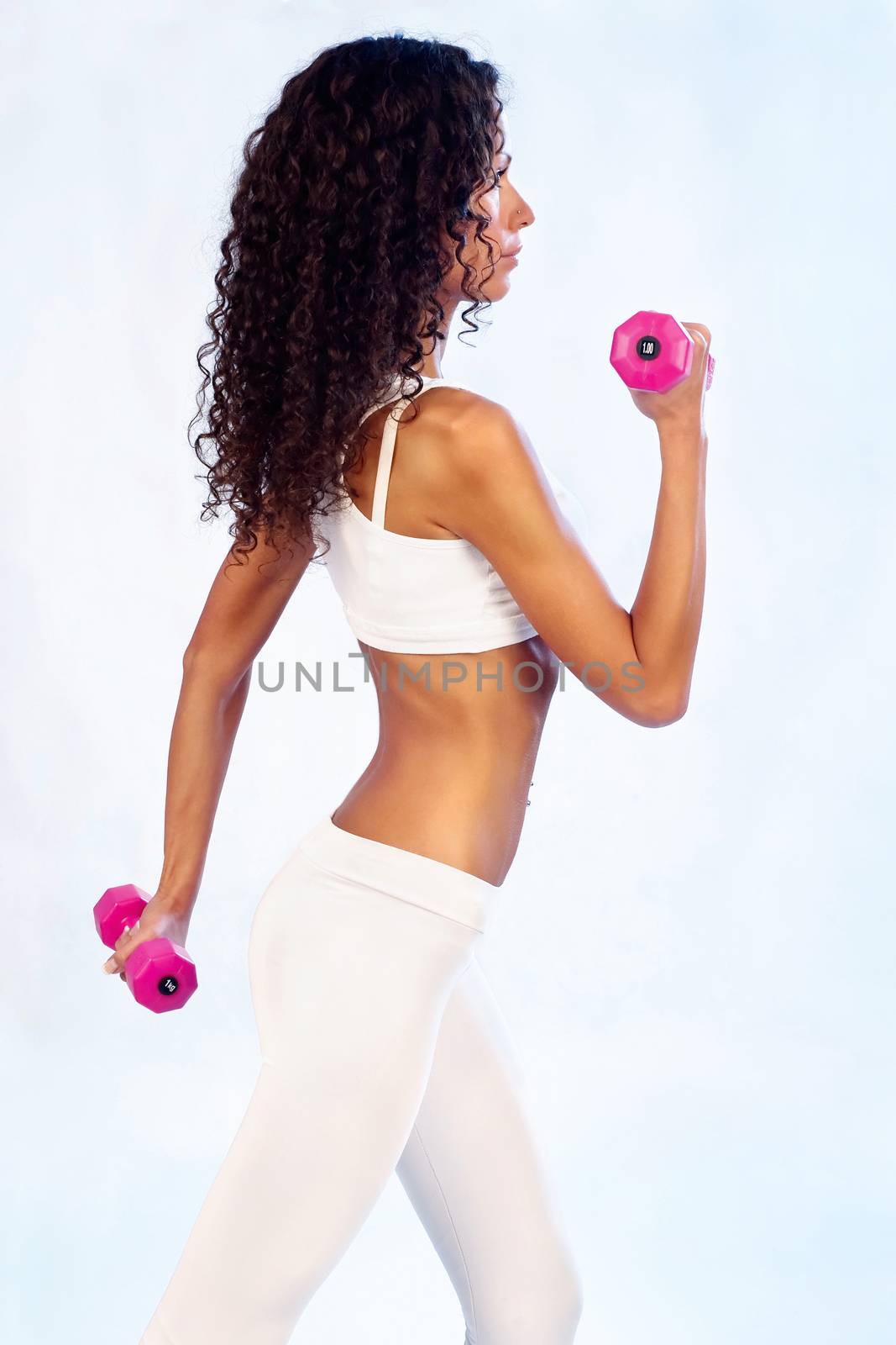 Young woman doing fitness exercises with weights, side view