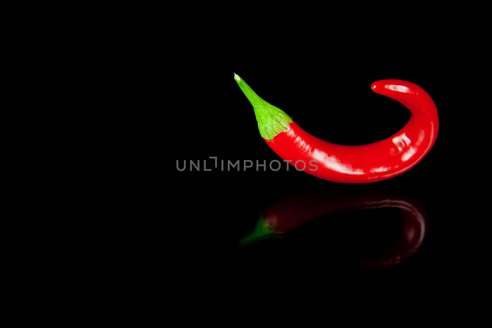 Red hot chili pepper on black background with reflection