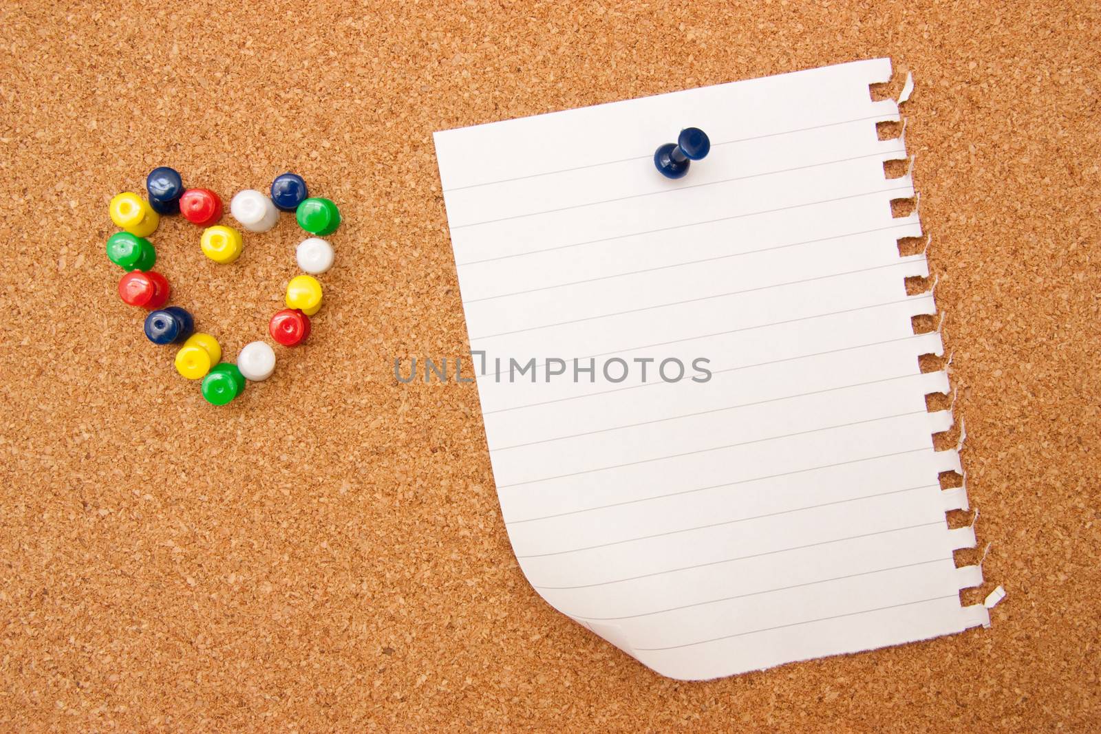 Corkboard with pushpins as heart and white note