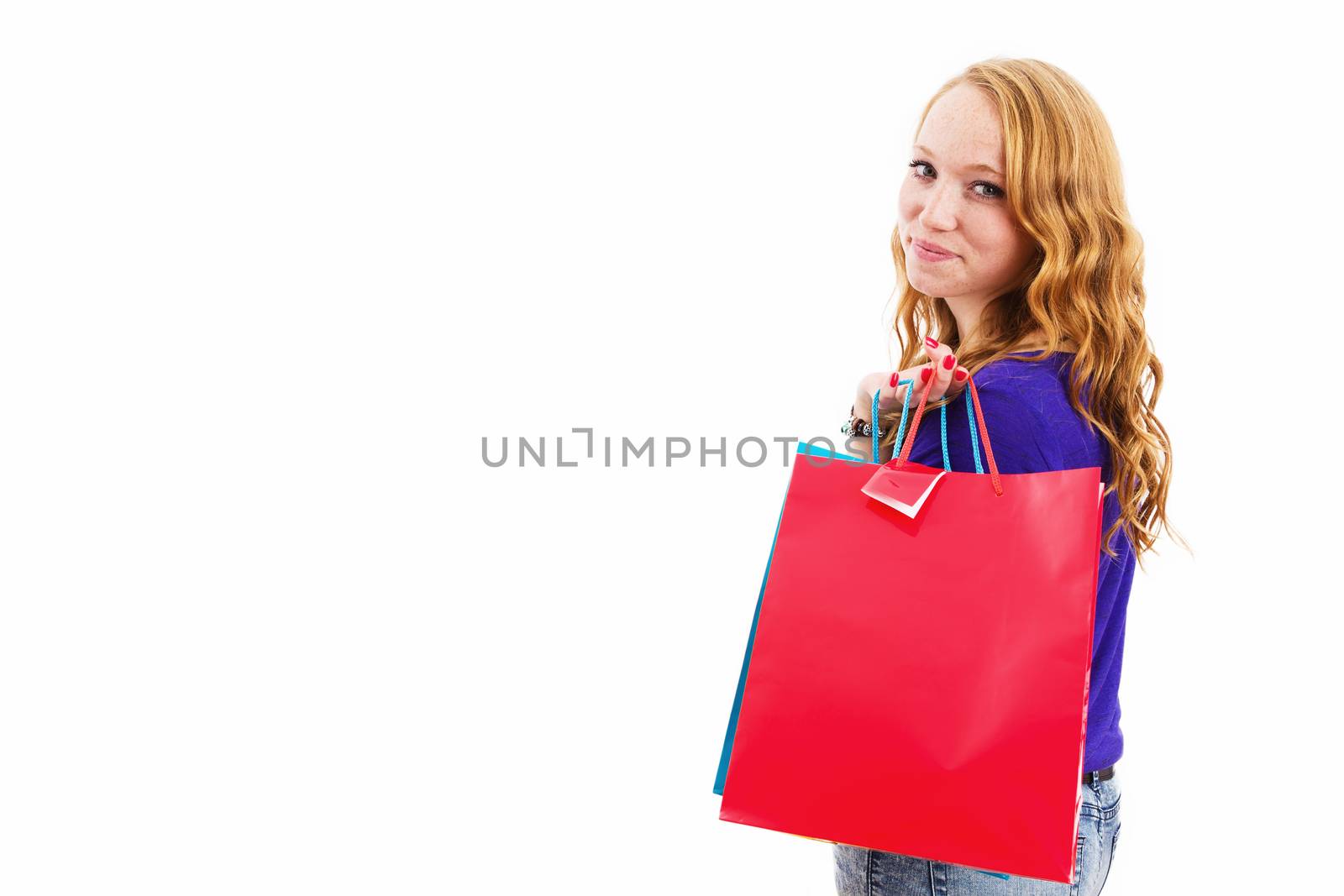 smiling redhead woman with shopping bags on white background with copyspace