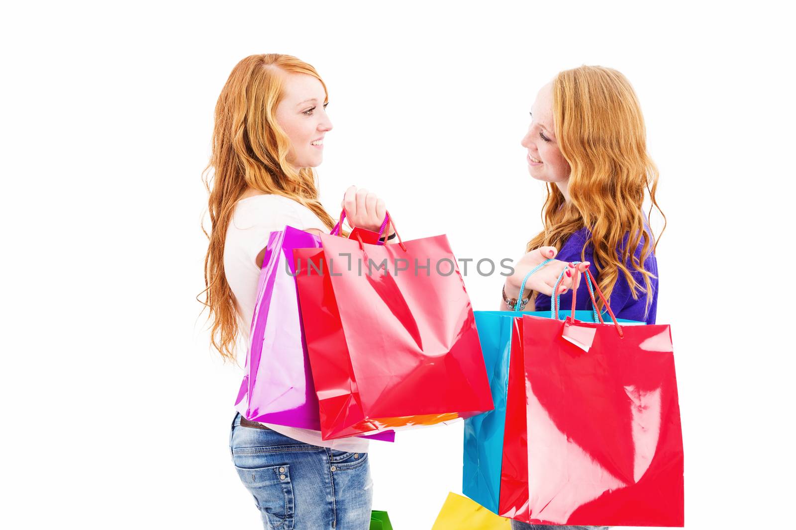 two chatting redhead women with shopping bags on white background