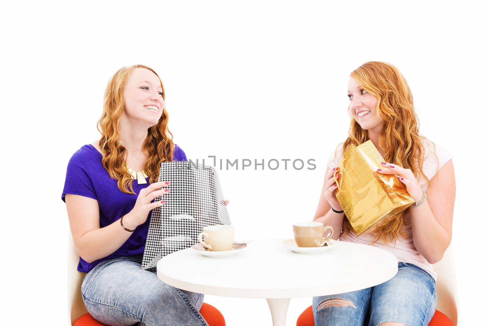 happy redhead women sitting at a coffee table with shopping bags on white background