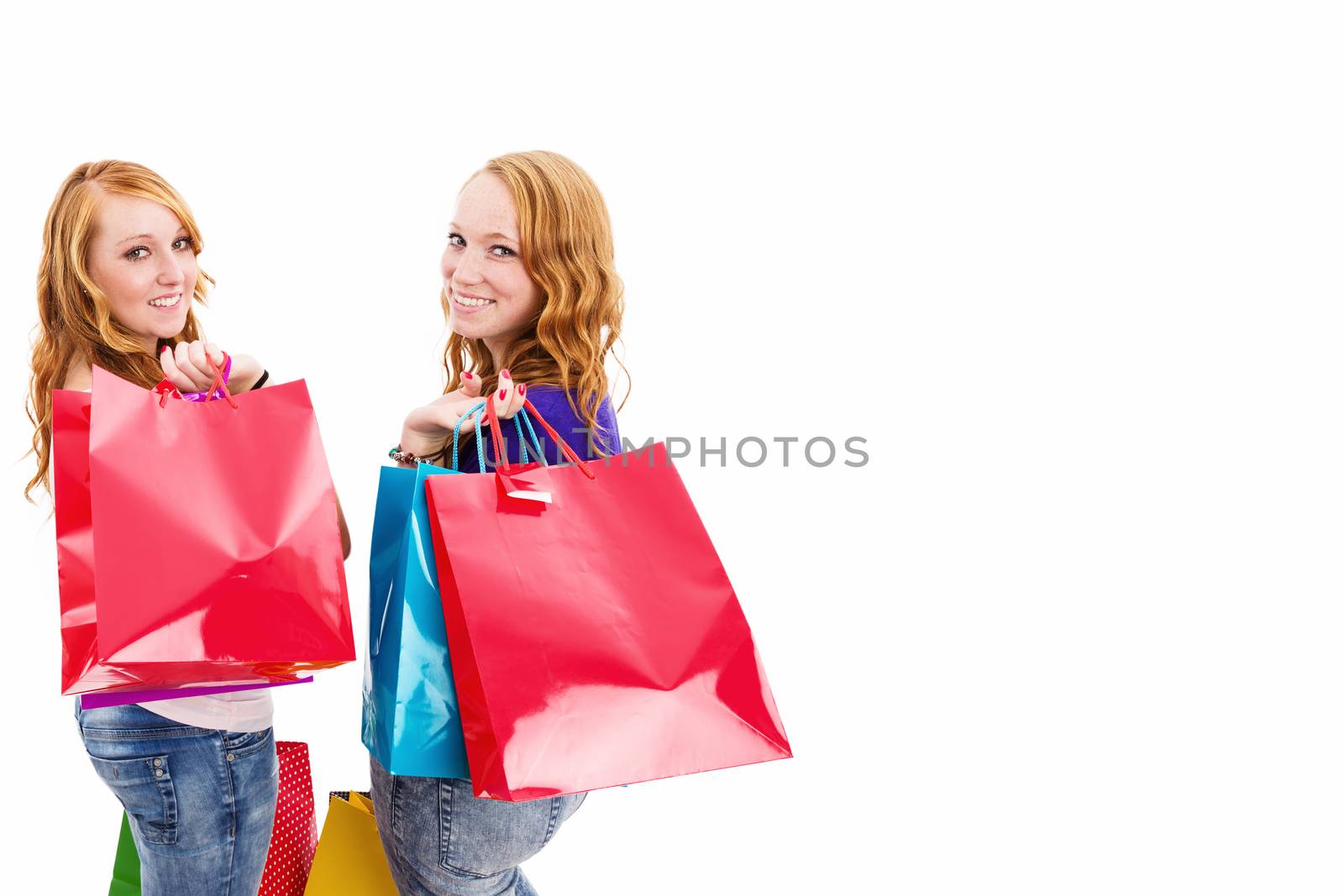 two happy redhead women with shopping bags turning around on white background