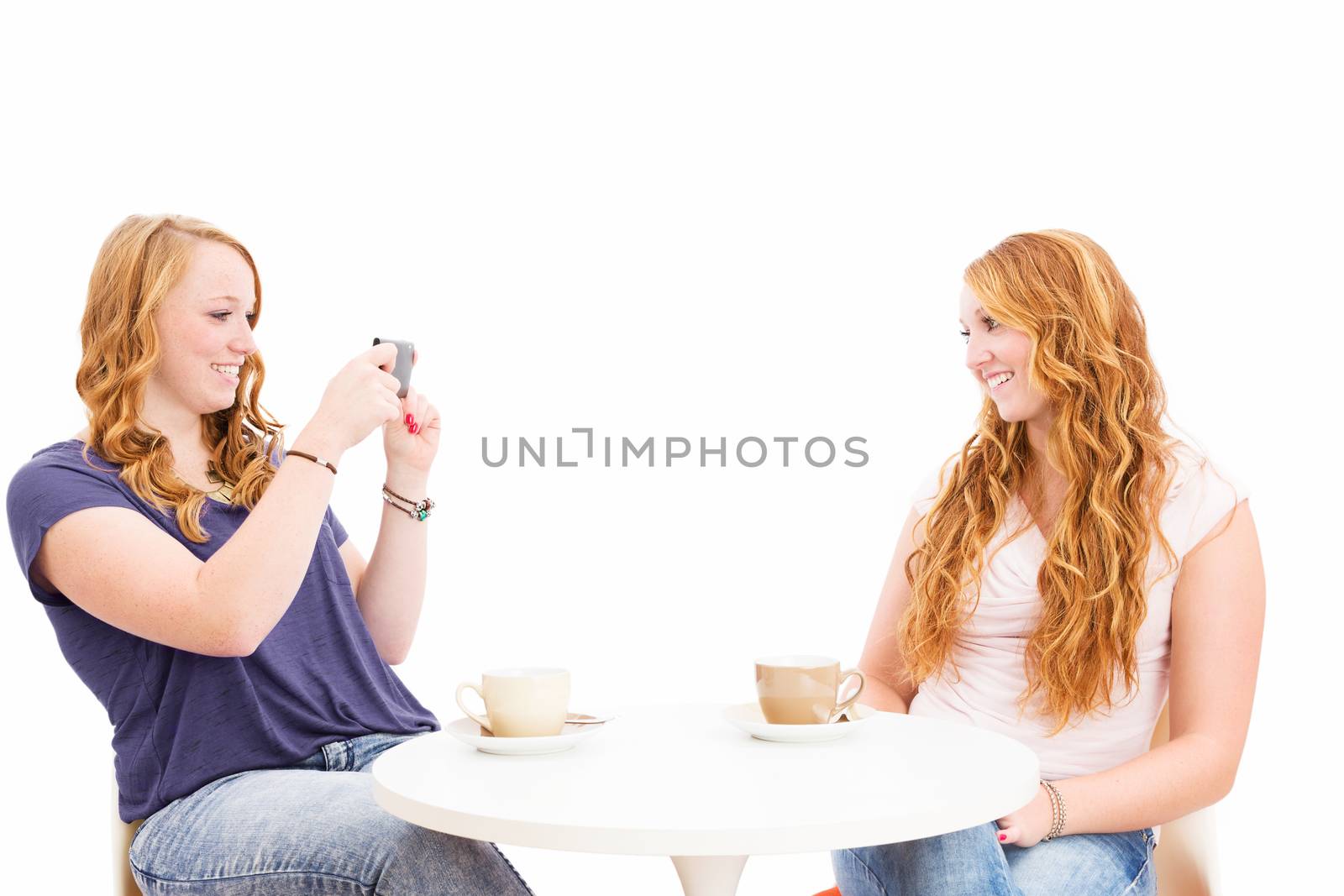 redhead woman making photos of her happy friend on white background
