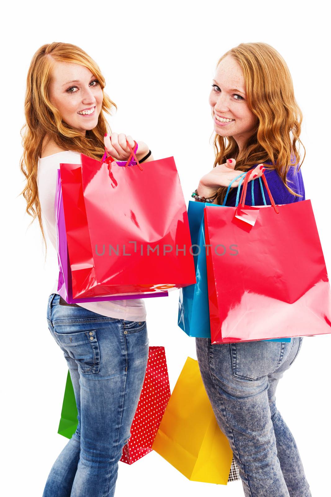 two happy women with shopping bags turning around on white background