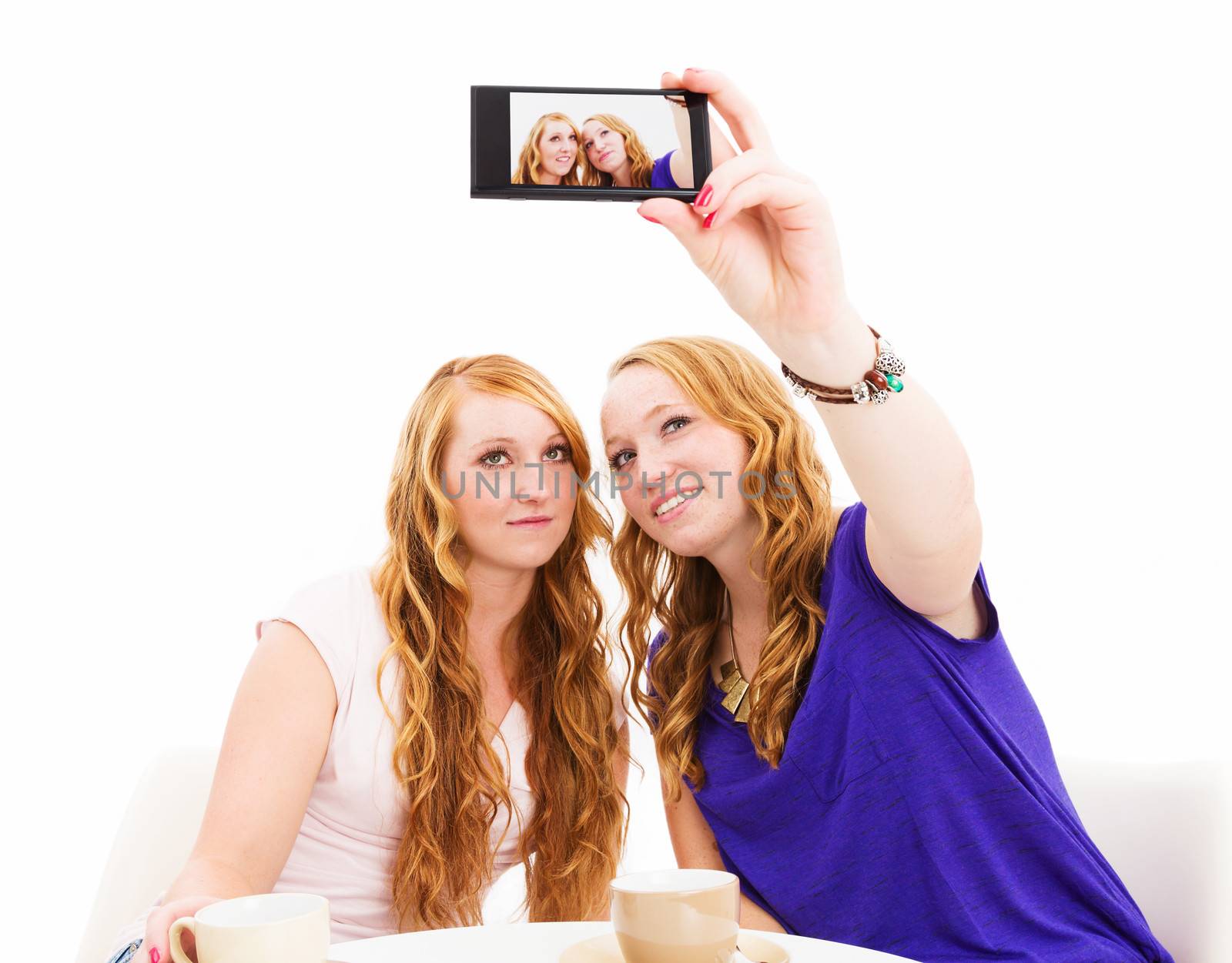 female redhead friends making photos of themselves on white background