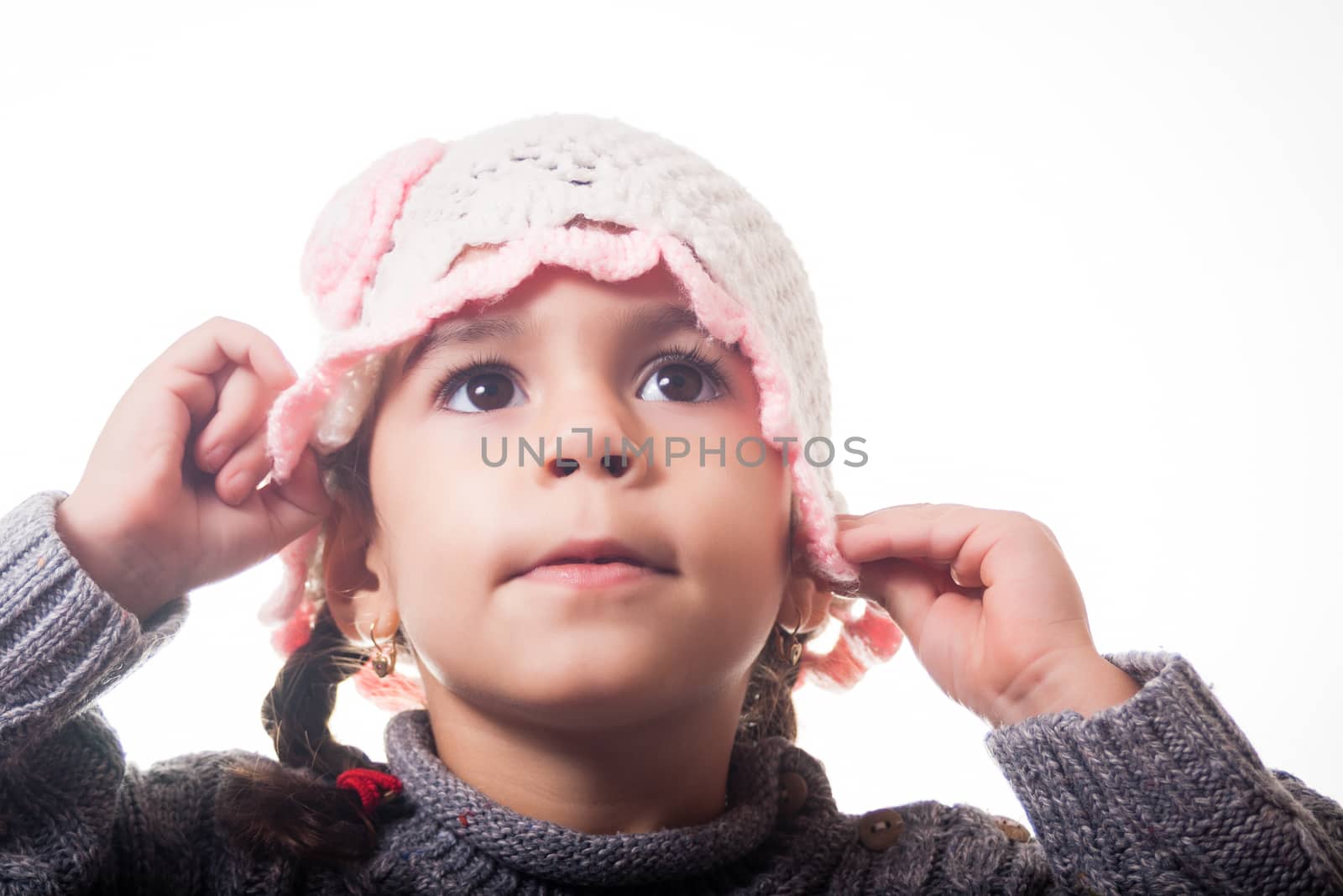 Girl arranging her knitted hat, on white background.