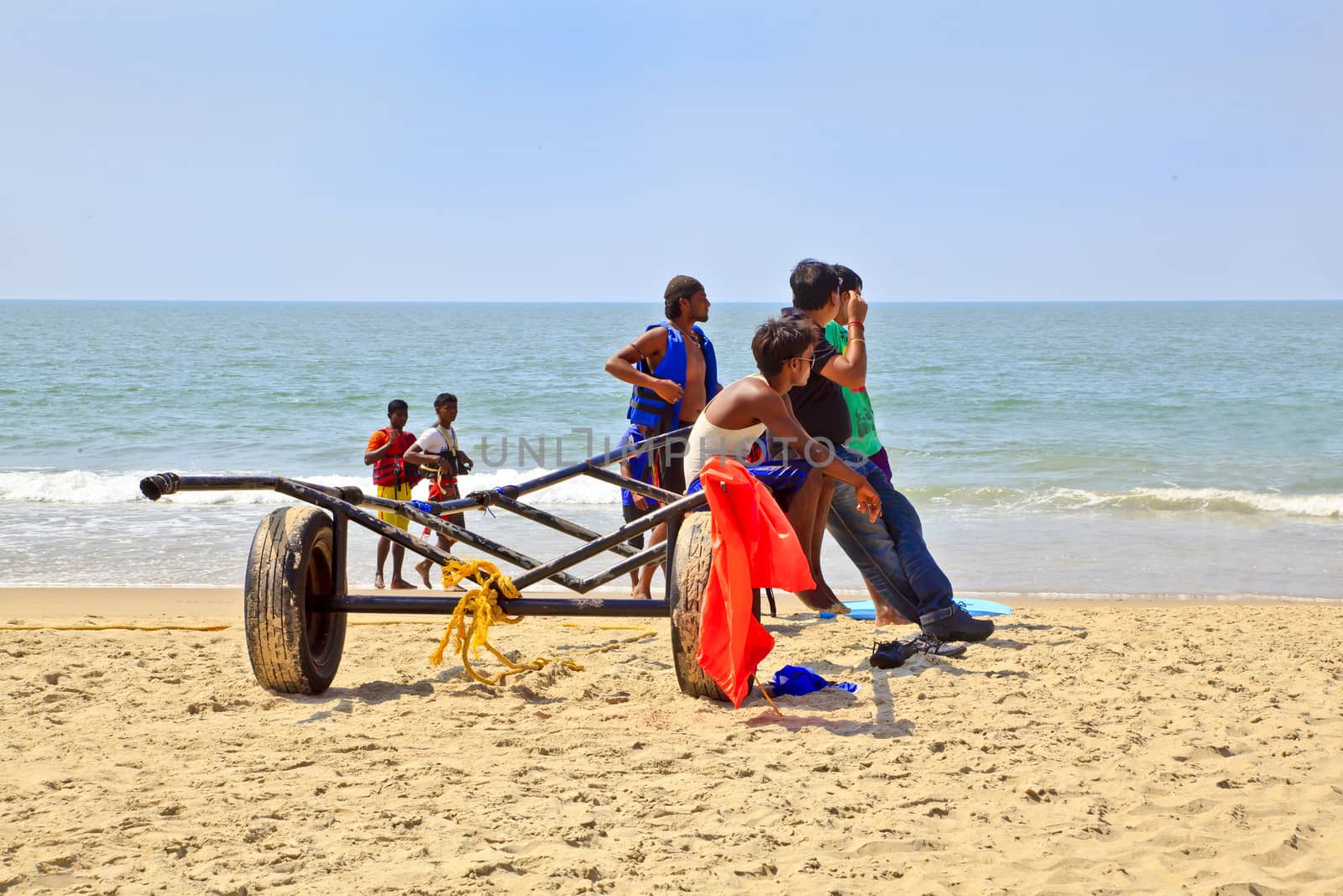 Horizontal Beach tropical landscape of para gliding sales assistants sat on a trailer waiting for the next fare under the mid day Indian sun. Shot location Uttorda Beach, Goa, India