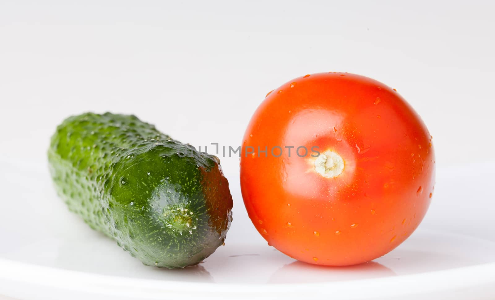 Red tomato and green cucumber on white
