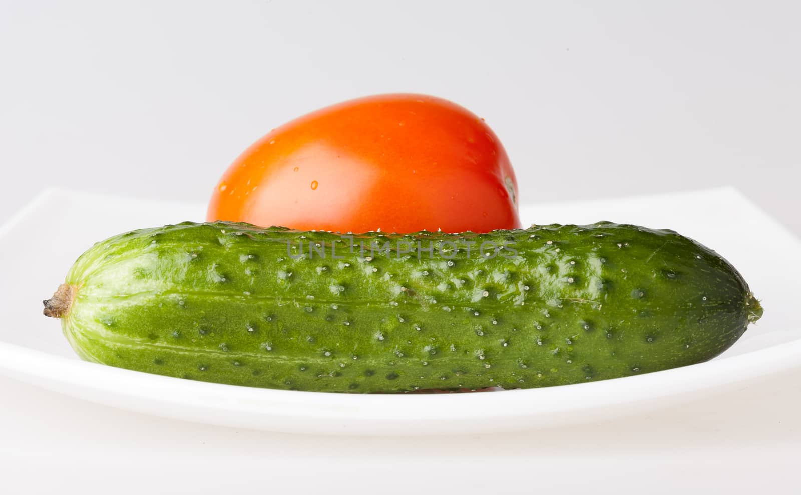 Red tomato and green cucumber on white