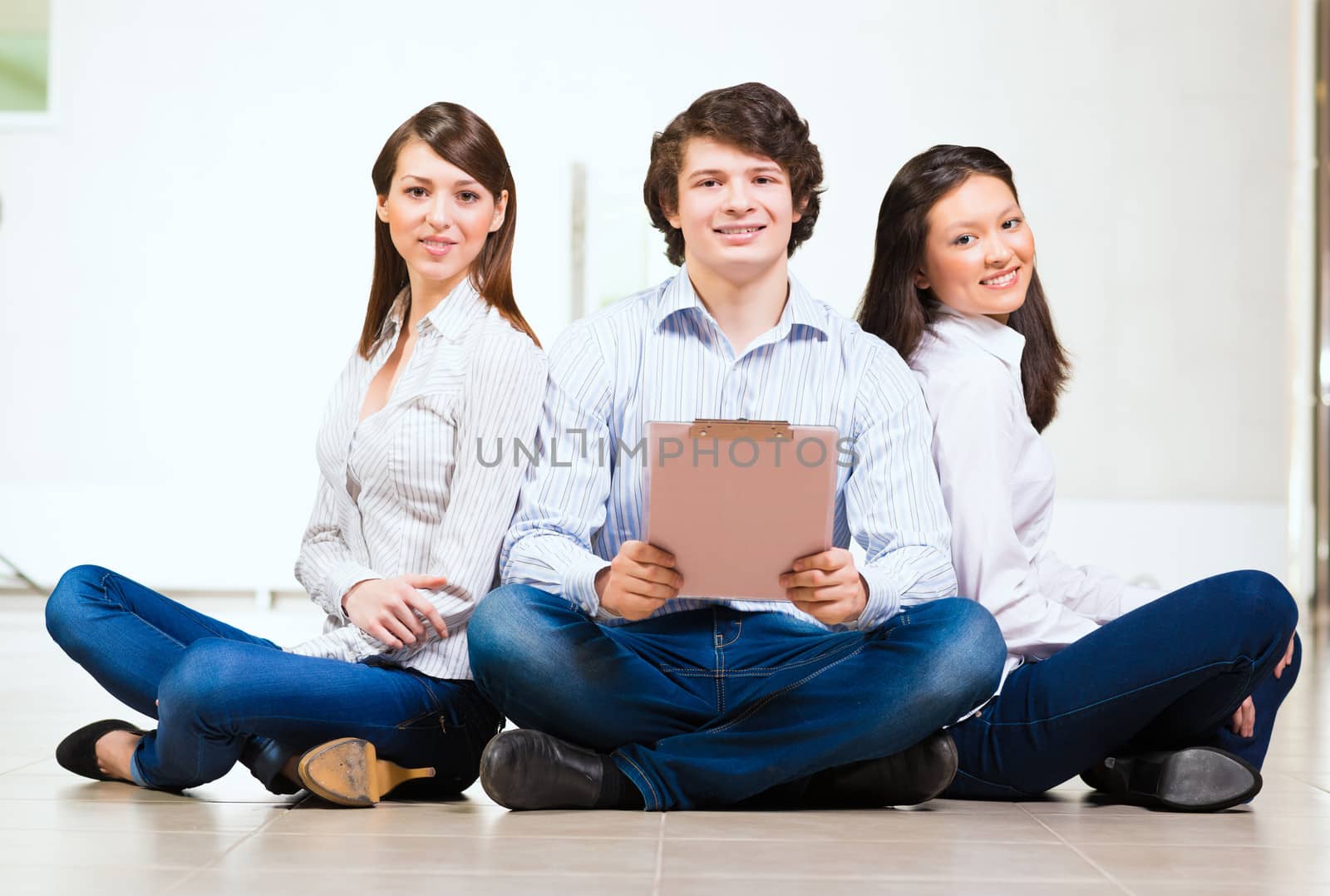 portrait of a group of young people sitting on the floor, man and two attractive women