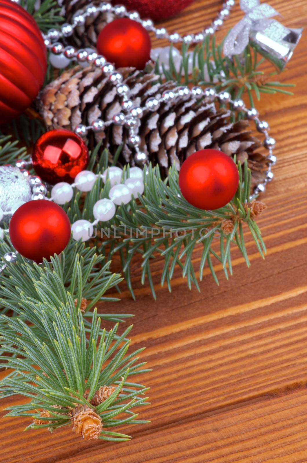 Frame of Spruce Branch and Fir Cones with Red and Silver Baubles, Bows, Pearl and Silver Beads closeup on Wooden background