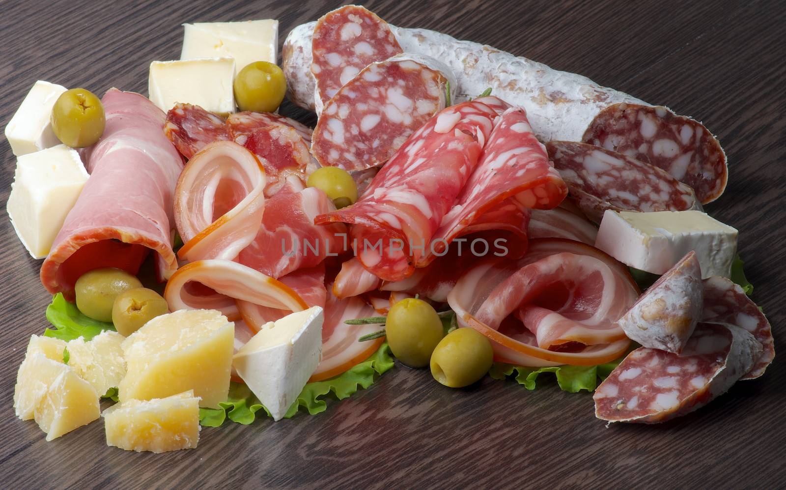 Arrangement of Delicatessen Cold Cuts with Smoked Ham, Pepperoni, Salami, Finocchiona, Green Olives, Grana Padano and Camembert Cheese closeup on Dark Wooden background