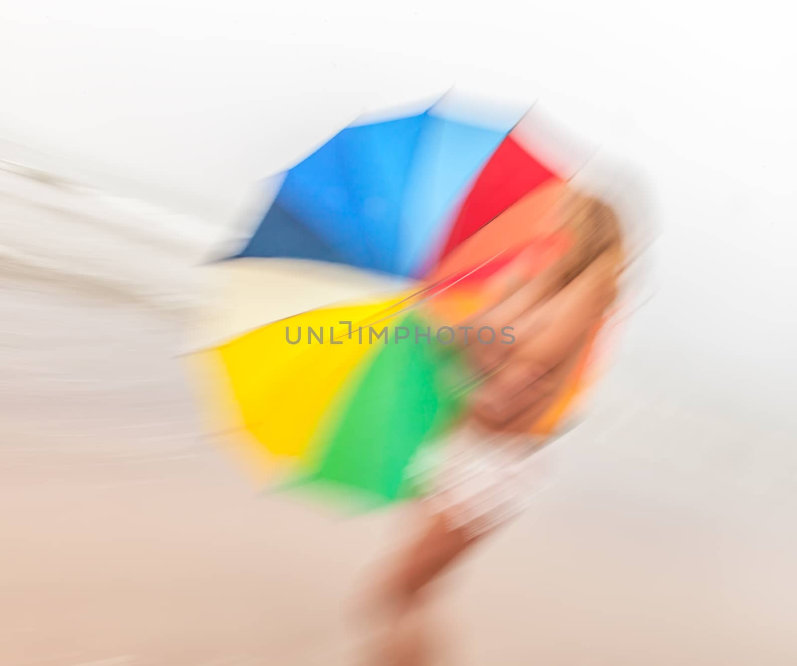 Rain and wind. Abstract image of girl with colorful umbrella against the sea.  Intentional motion blur