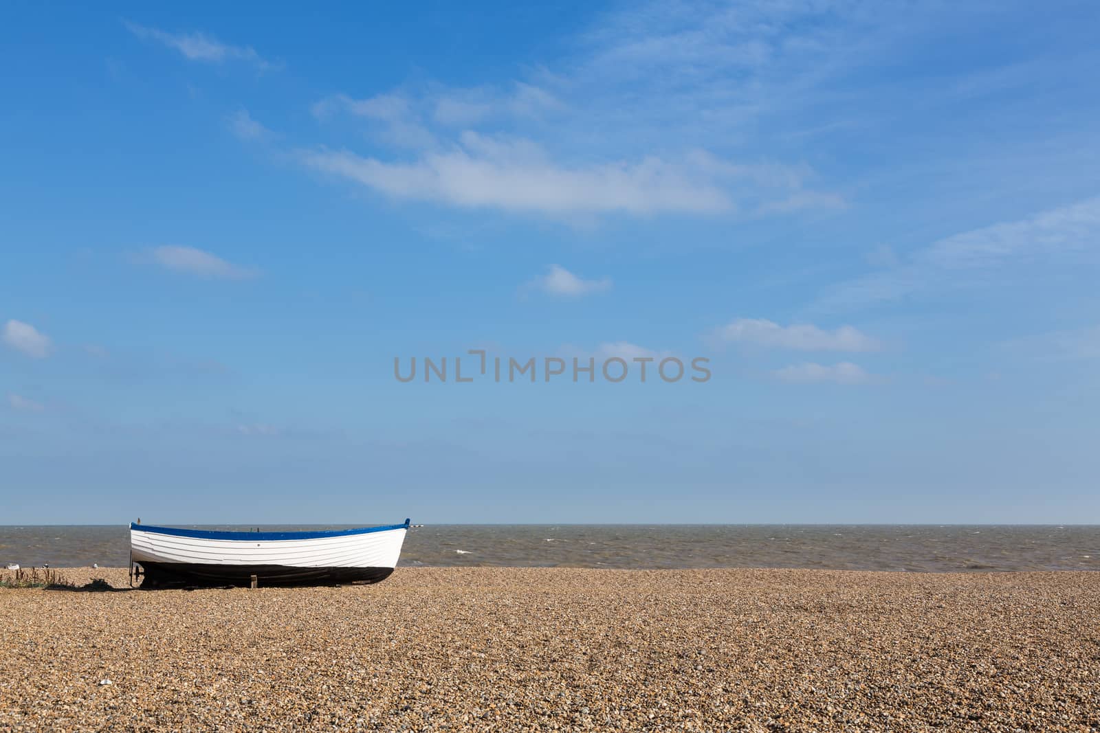 Ancient wooden painted fishing boat on pebble beach by North Sea in Aldeburgh Suffolk on East coast of England