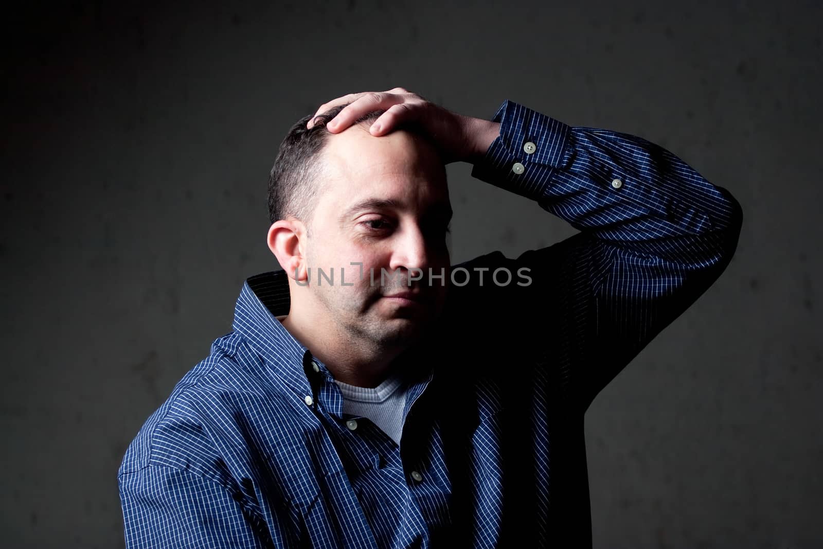 A middle aged man with a contemplative look on his face.  He could be worried or depressed about something.