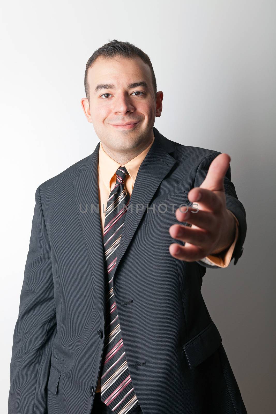 Friendly business man greeting the viewer and extending his hand out for a handshake.