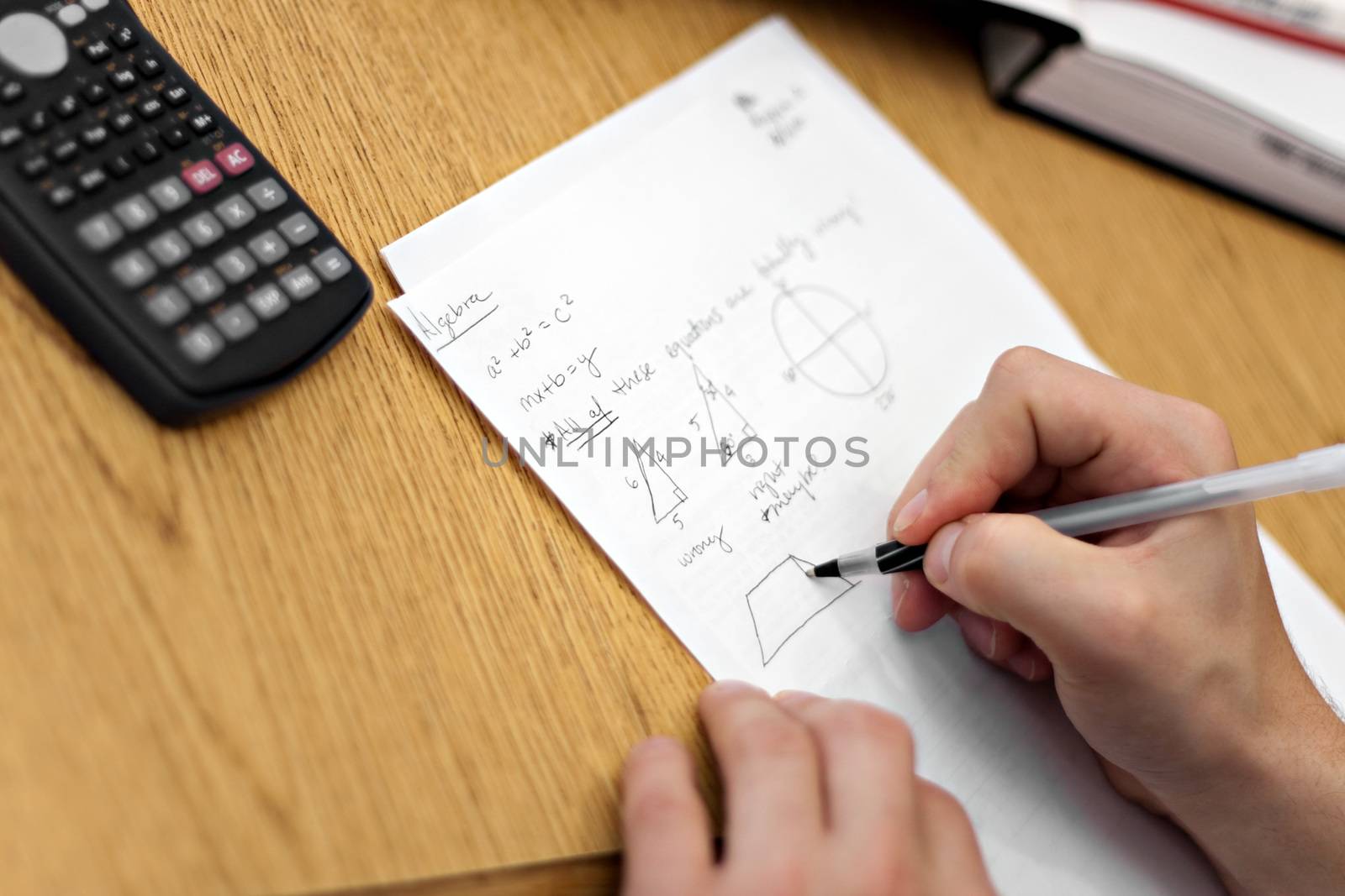 A young man working out mathematical equations on paper.