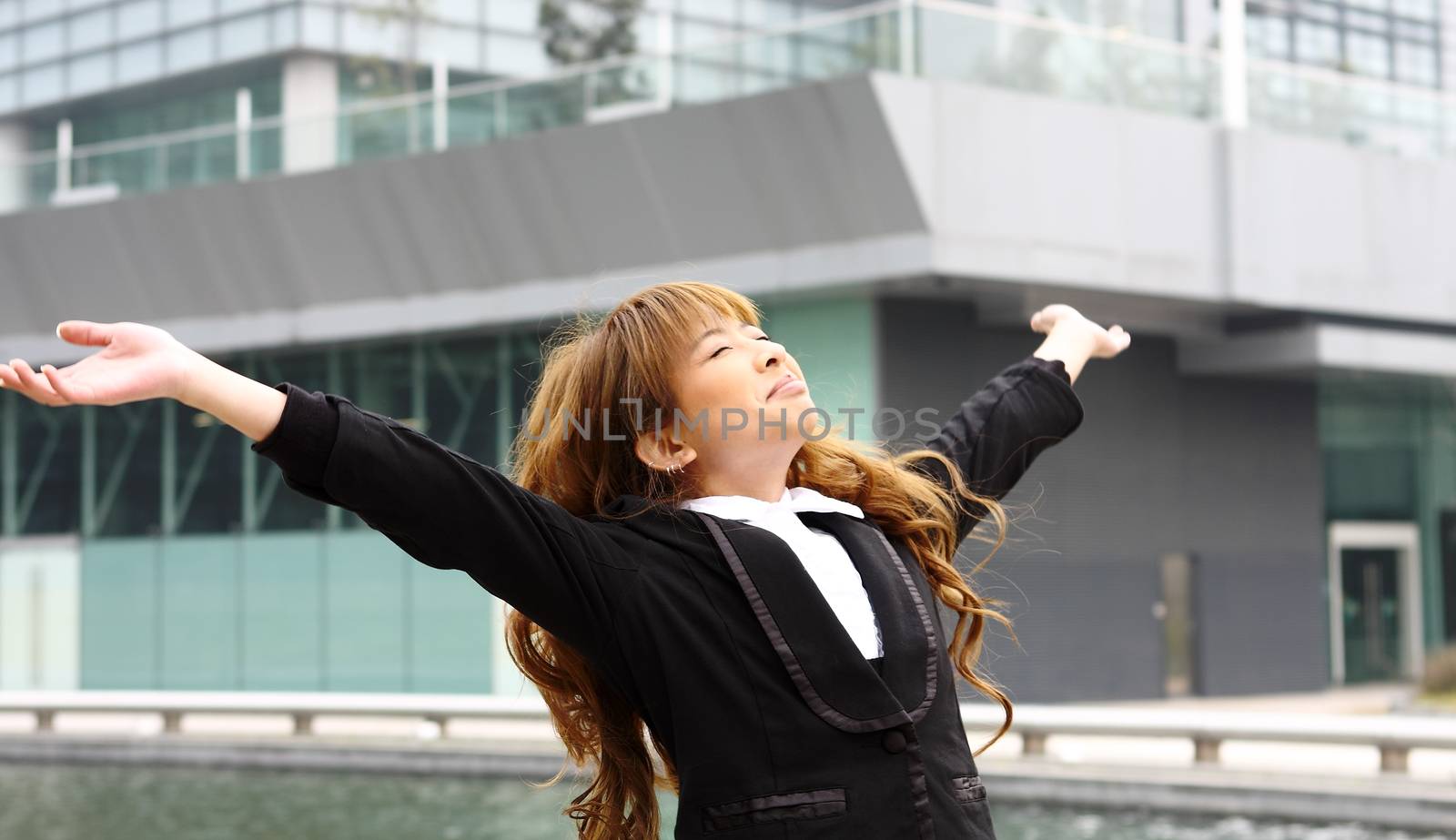 Woman relaxing with arms open enjoying her freedom and office building background