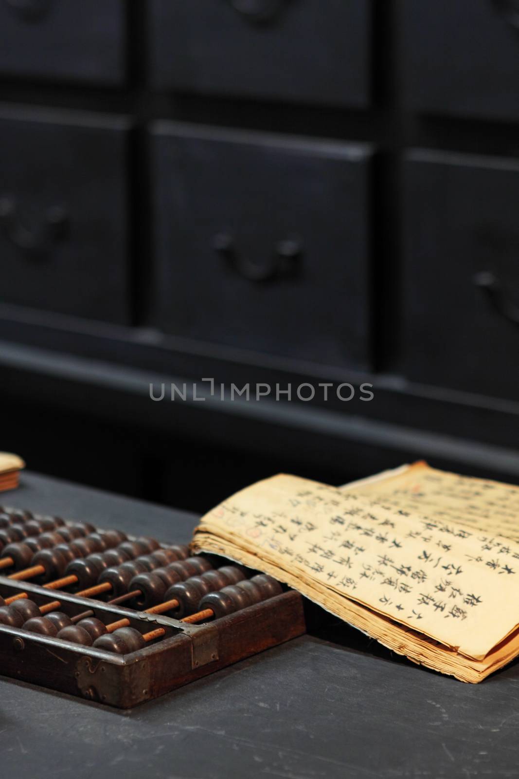 abacus and book on the table in a chinese old shop by cozyta