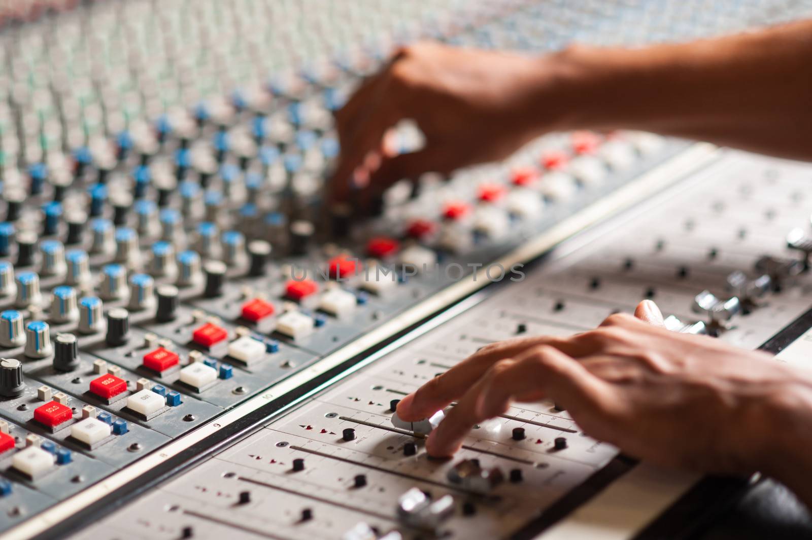 An expert adjusting audio mixing console