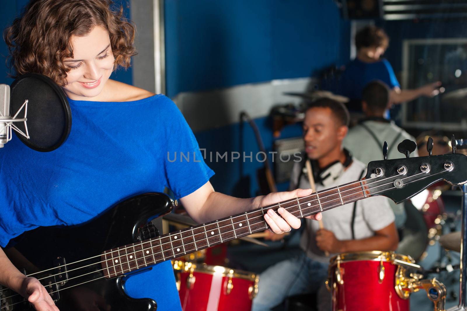 Woman playing guitar in recording studio by stockyimages