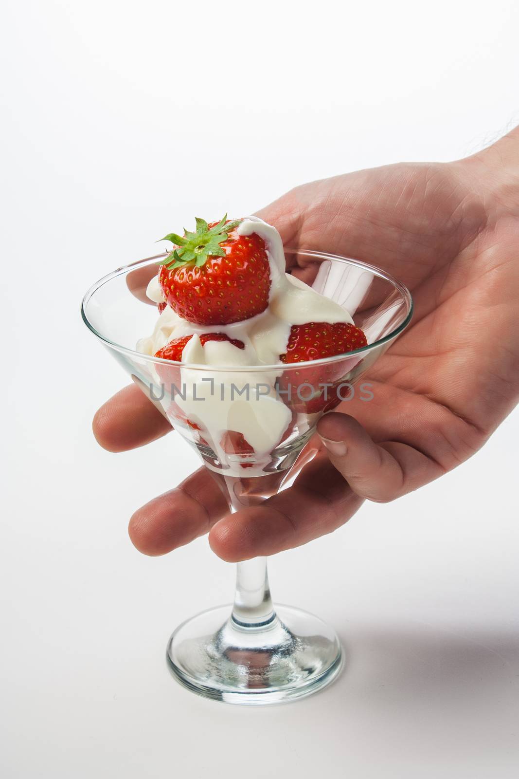 Strawberries with whipped cream and mint leaf in a glass on a white background