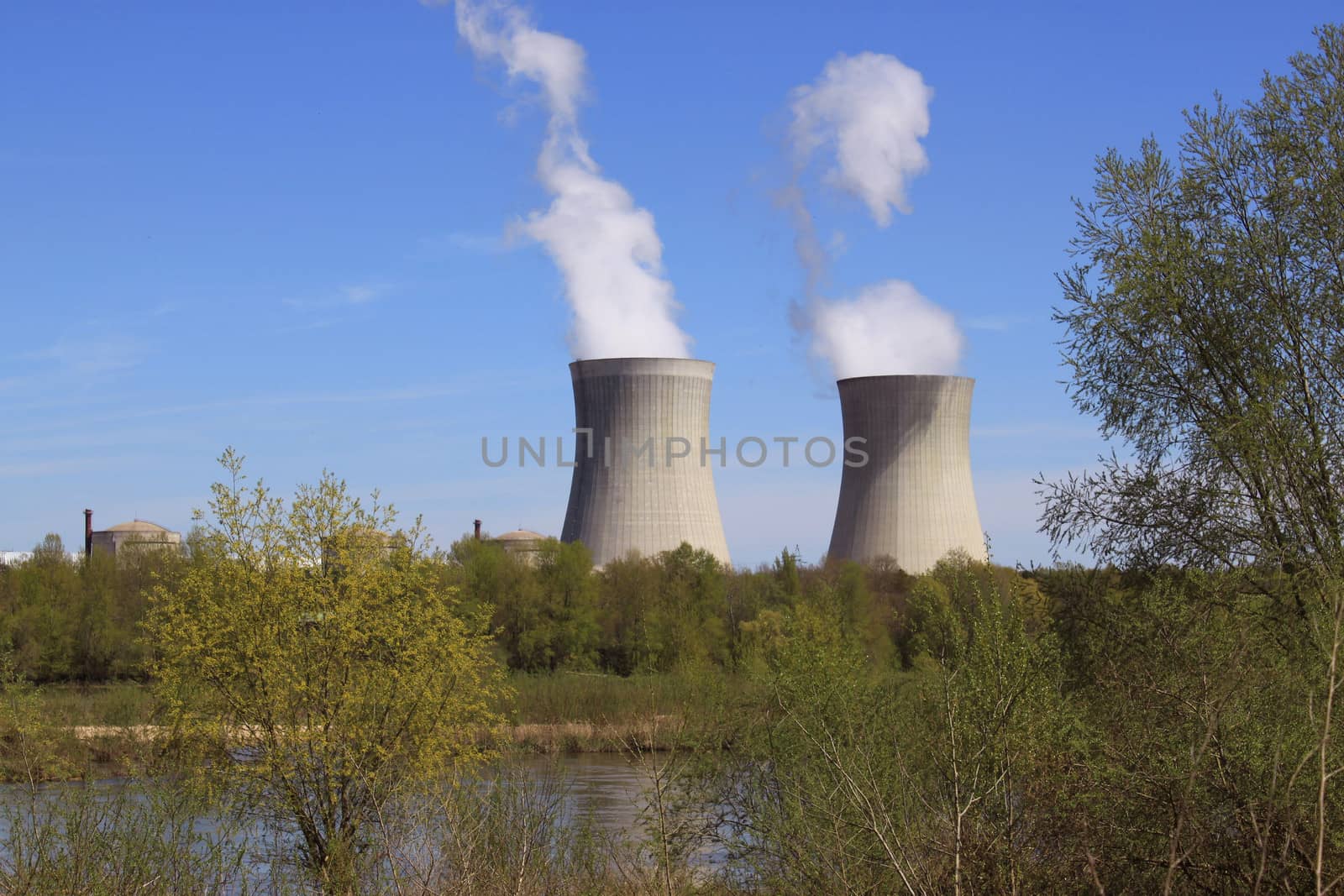 photo of an operating nuclear power plant on the banks of a river surrounded by trees