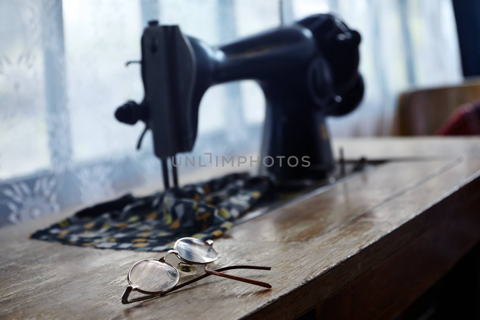 Old eyeglasses and sewing machine near the window