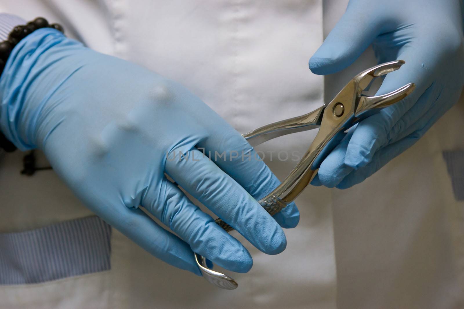 dentists hands in blue medical gloves with dental tools